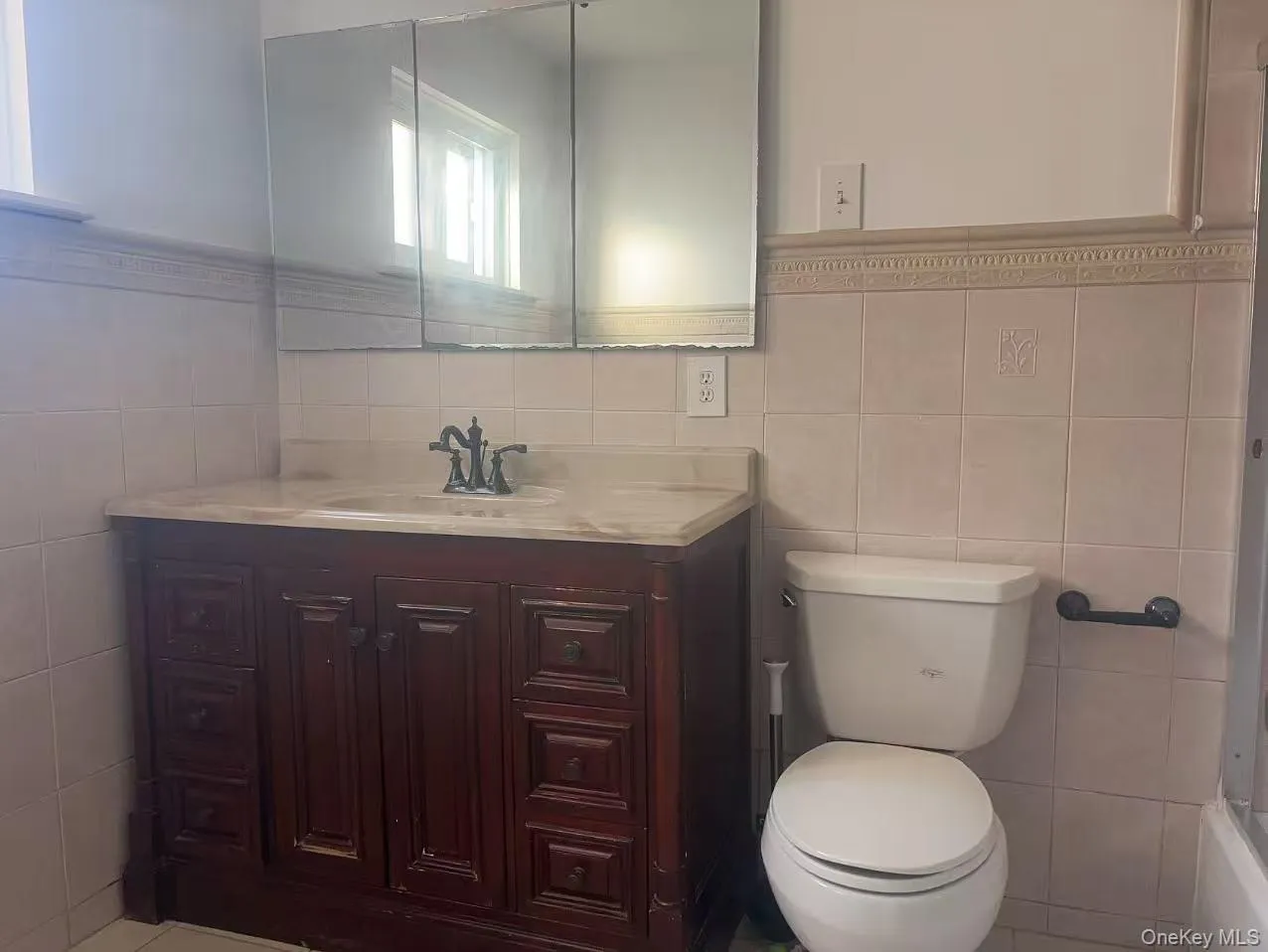 Bathroom with tile walls, vanity, and a wainscoted wall Bathroom with tile walls, vanity, and a wainscoted wall