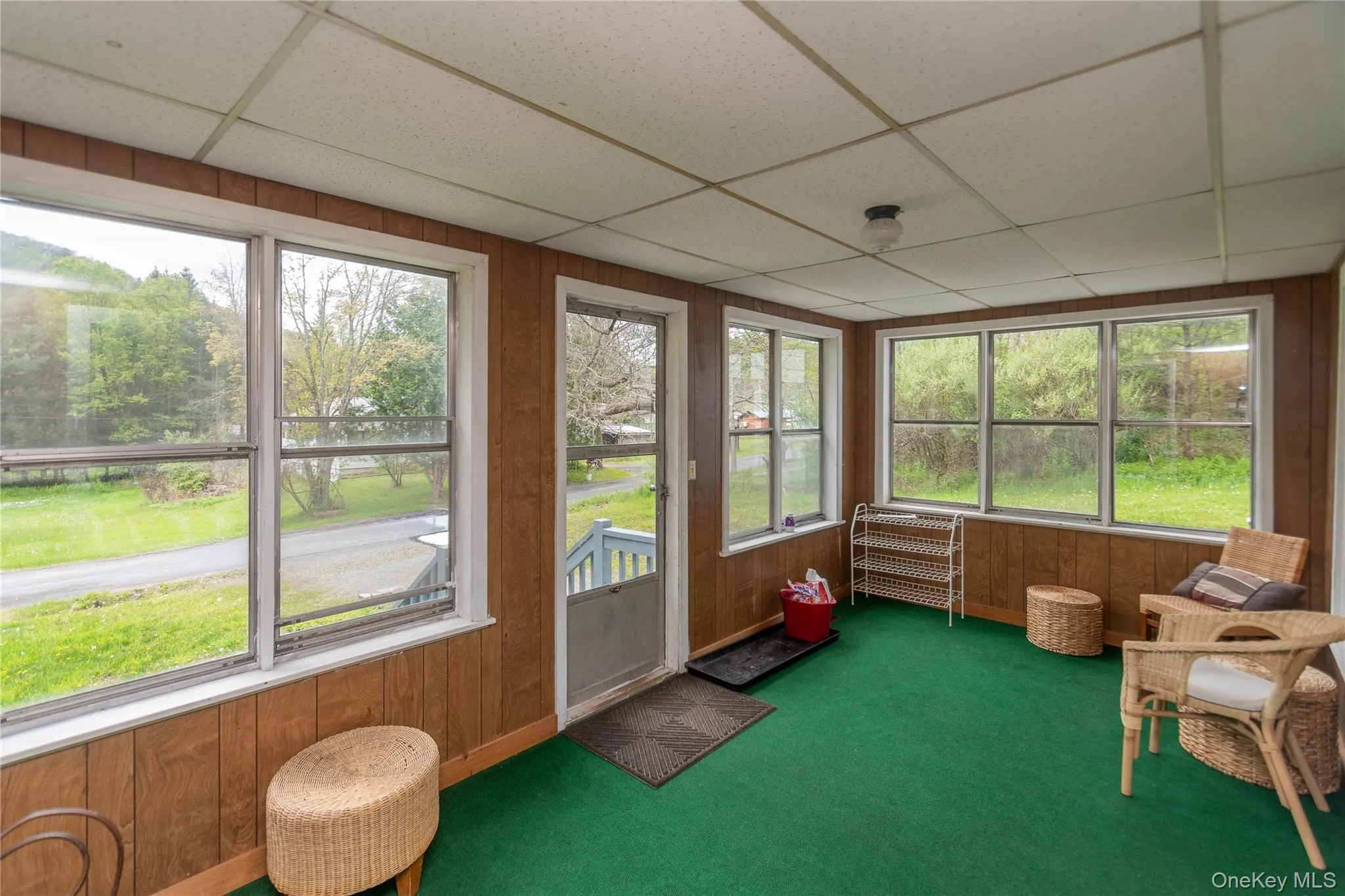 Sunroom featuring wood-finish wall paneling and green carpeting Sunroom featuring wood-finish wall paneling and green carpeting