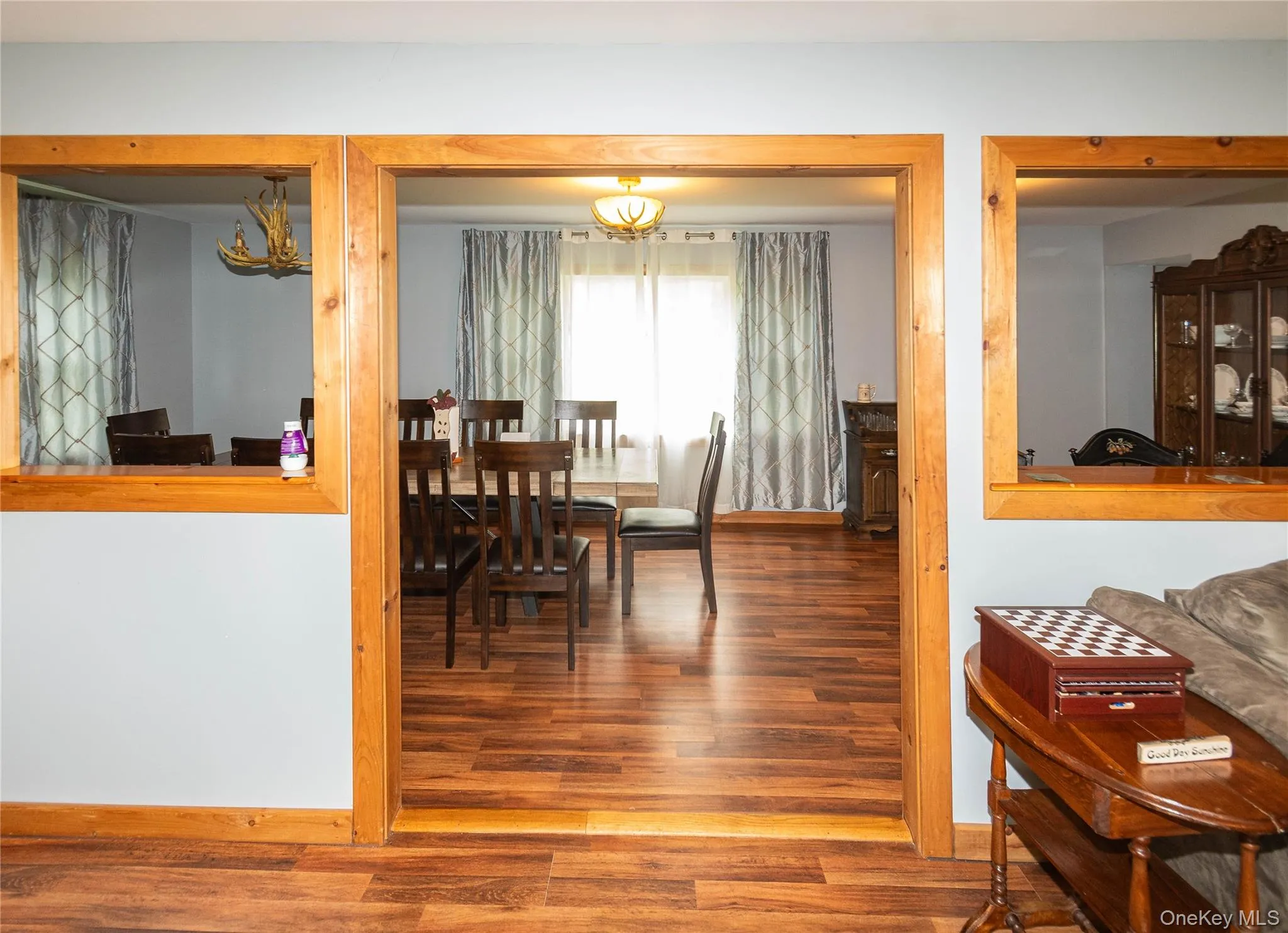Spacious room featuring wood-finish flooring, light blue wall paint, and natural wood trim around openings Spacious room featuring wood-finish flooring, light blue wall paint, and natural wood trim around openings