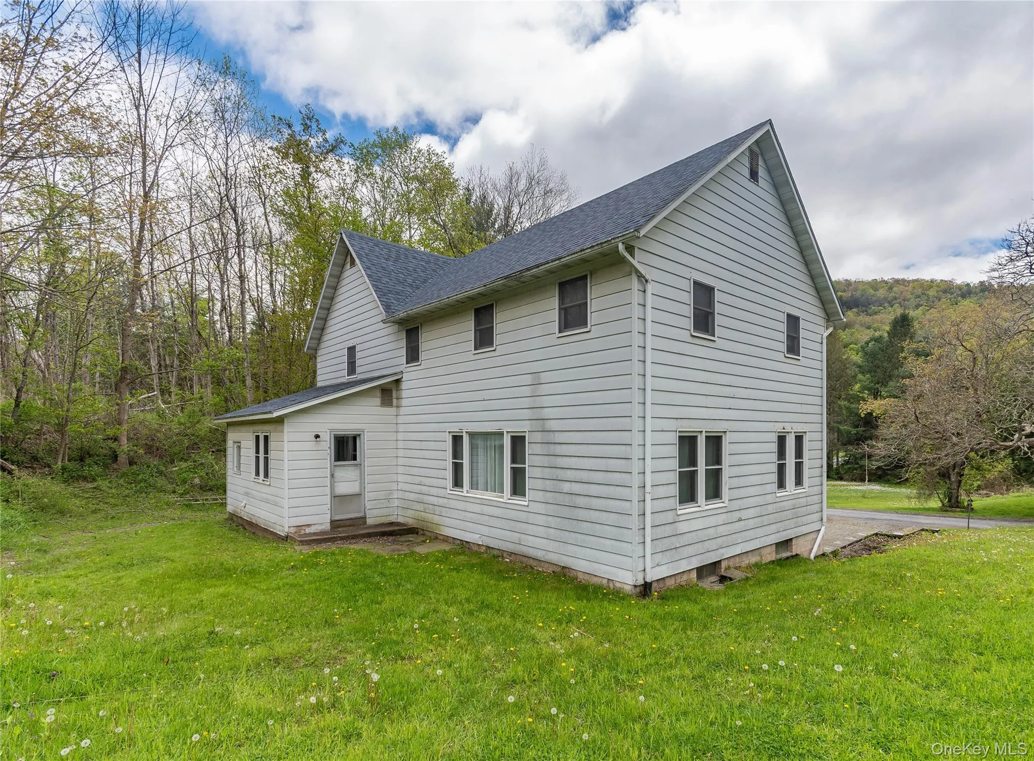 Two-story siding residence featuring a dark shingle roof and multiple windows Two-story siding residence featuring a dark shingle roof and multiple windows