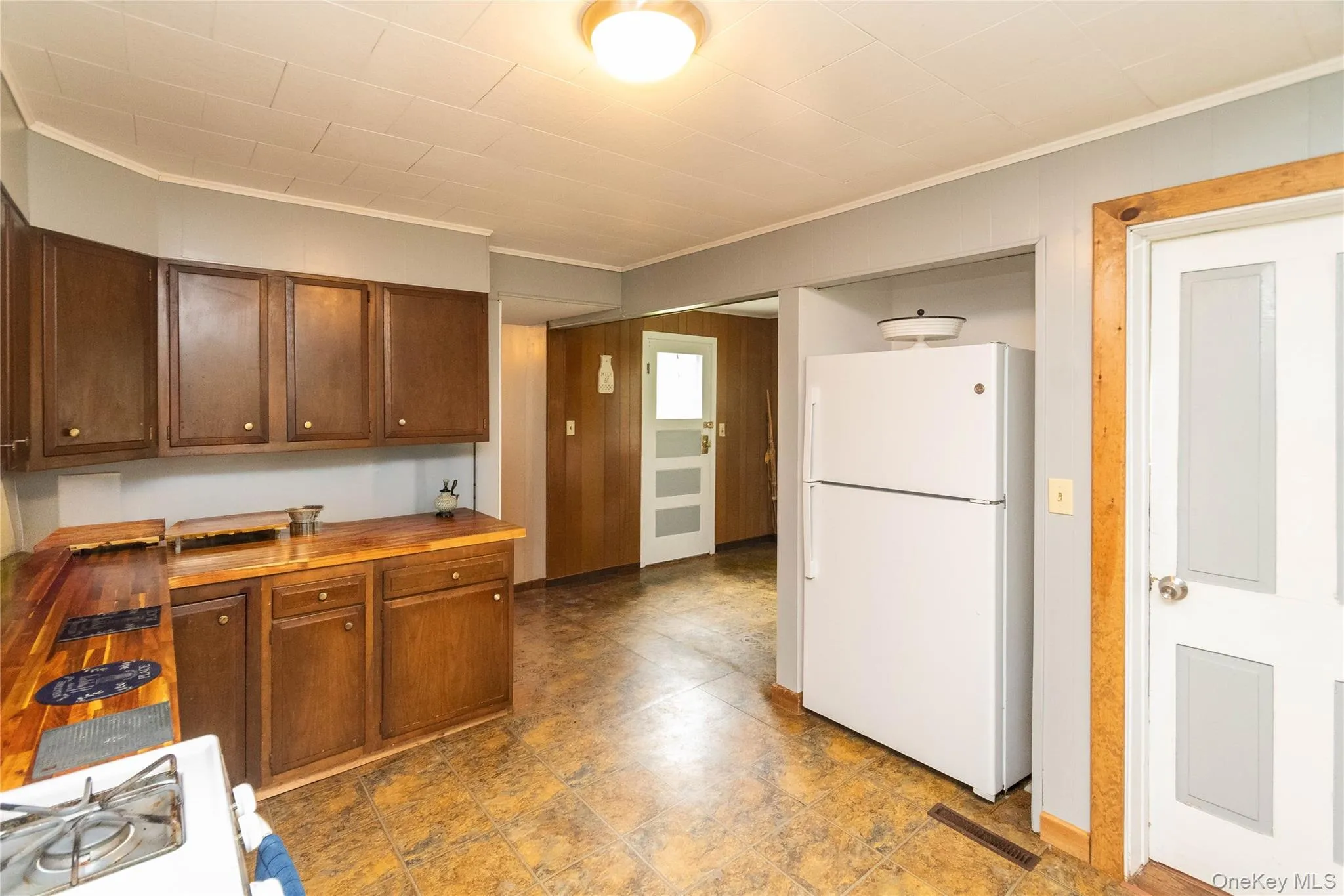 Kitchen featuring wood cabinetry, wood-finish countertops, and patterned floor tiling Kitchen featuring wood cabinetry, wood-finish countertops, and patterned floor tiling