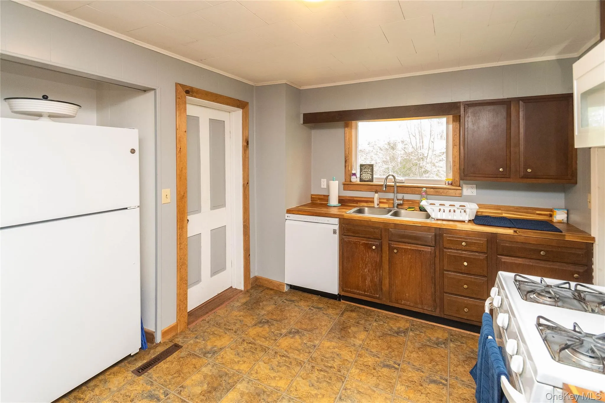 Kitchen featuring wood-finish countertops, wood cabinetry, and a double basin sink with a stainless steel faucet Kitchen featuring wood-finish countertops, wood cabinetry, and a double basin sink with a stainless steel faucet