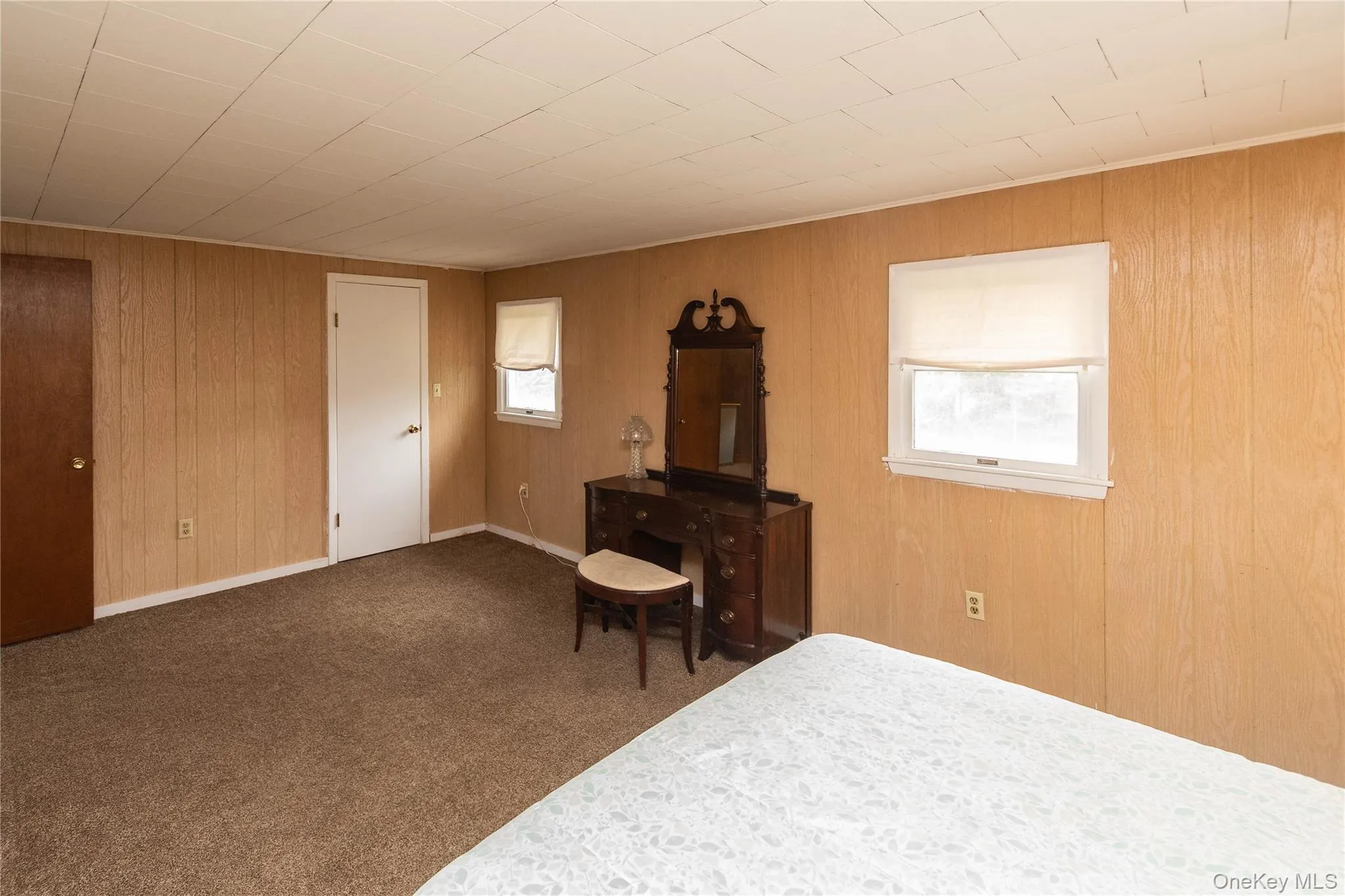 Room with wood-panel walls, neutral carpet, and white ceiling panels Room with wood-panel walls, neutral carpet, and white ceiling panels