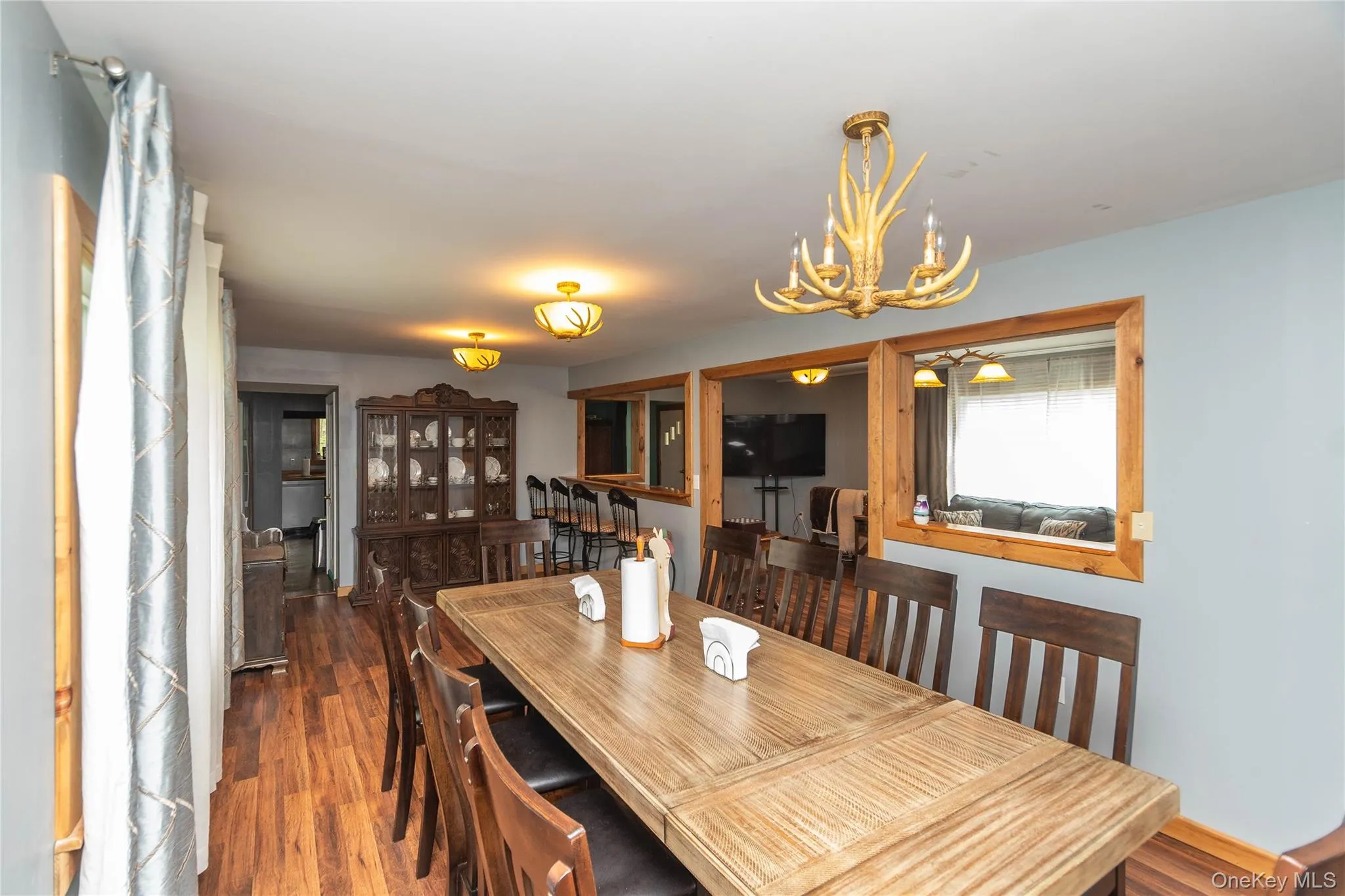 Dining area featuring wood-finish flooring, a decorative antler-style chandelier, and recessed display windows with wood trim Dining area featuring wood-finish flooring, a decorative antler-style chandelier, and recessed display windows with wood trim