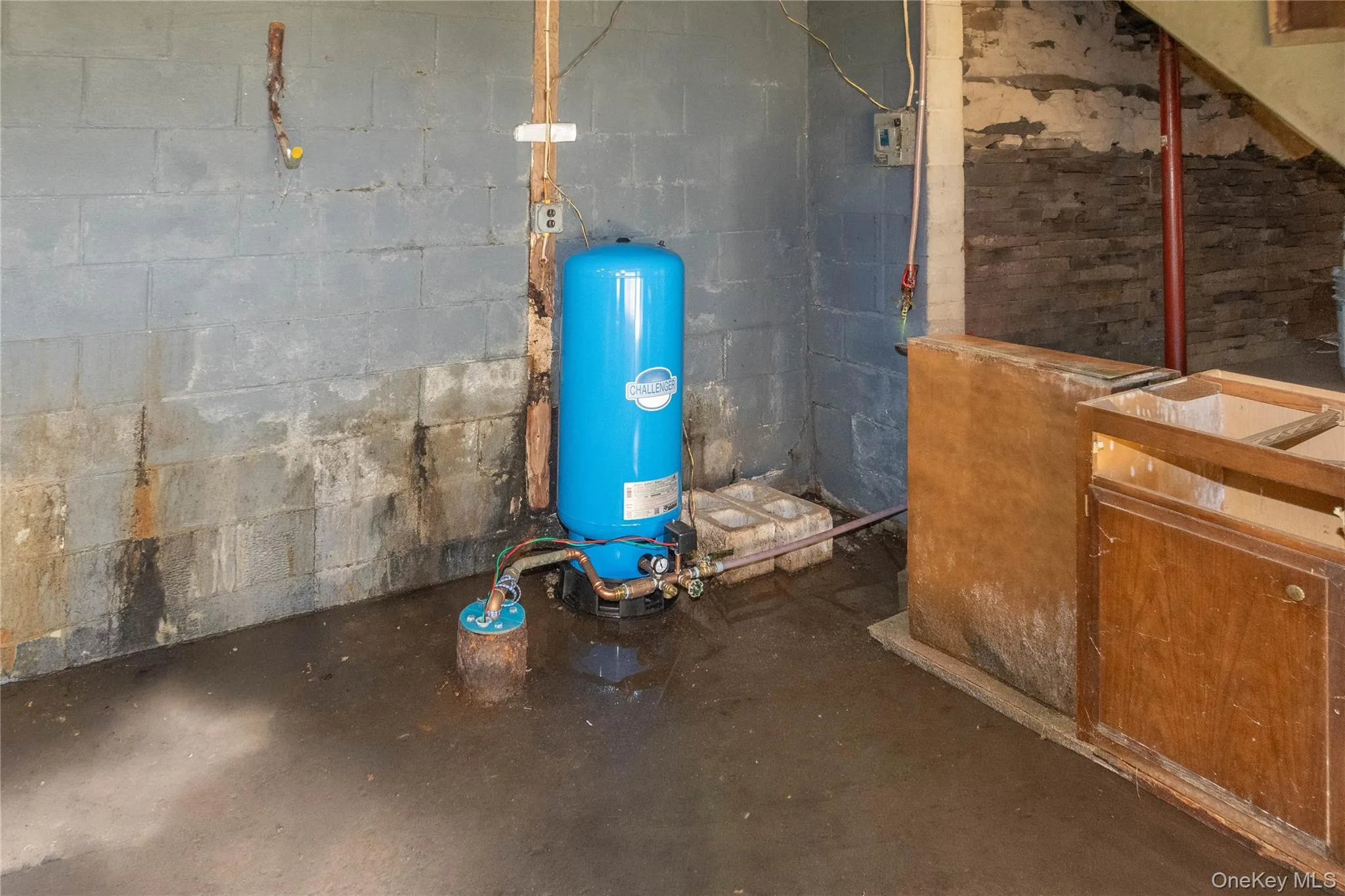 Basement utility area featuring a blue pressure tank and exposed piping Basement utility area featuring a blue pressure tank and exposed piping