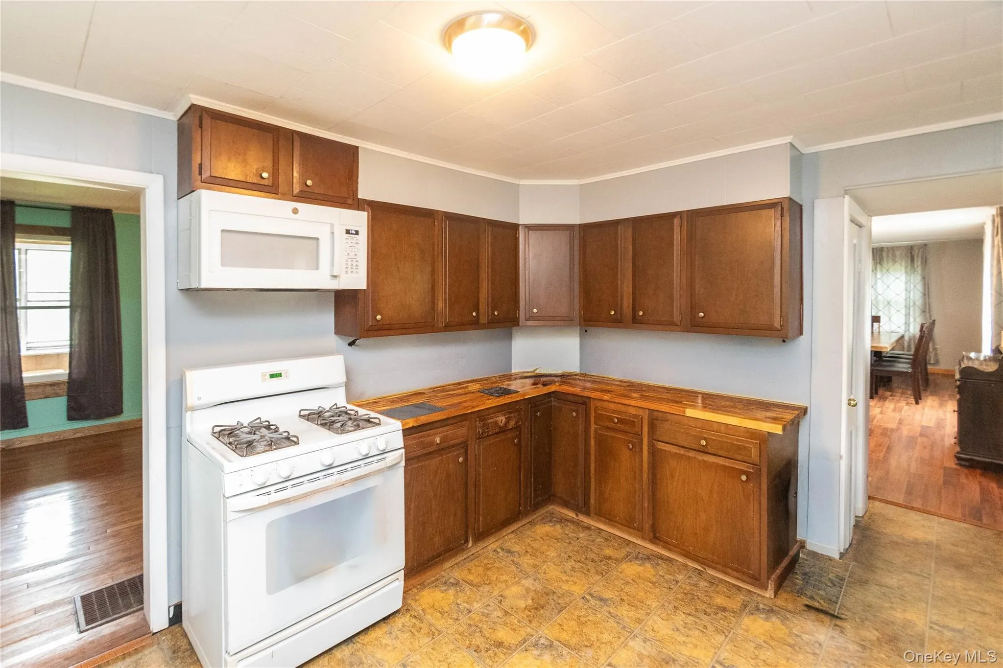 Kitchen featuring wood-finish cabinetry, a white gas range, and a white over-the-range microwave Kitchen featuring wood-finish cabinetry, a white gas range, and a white over-the-range microwave
