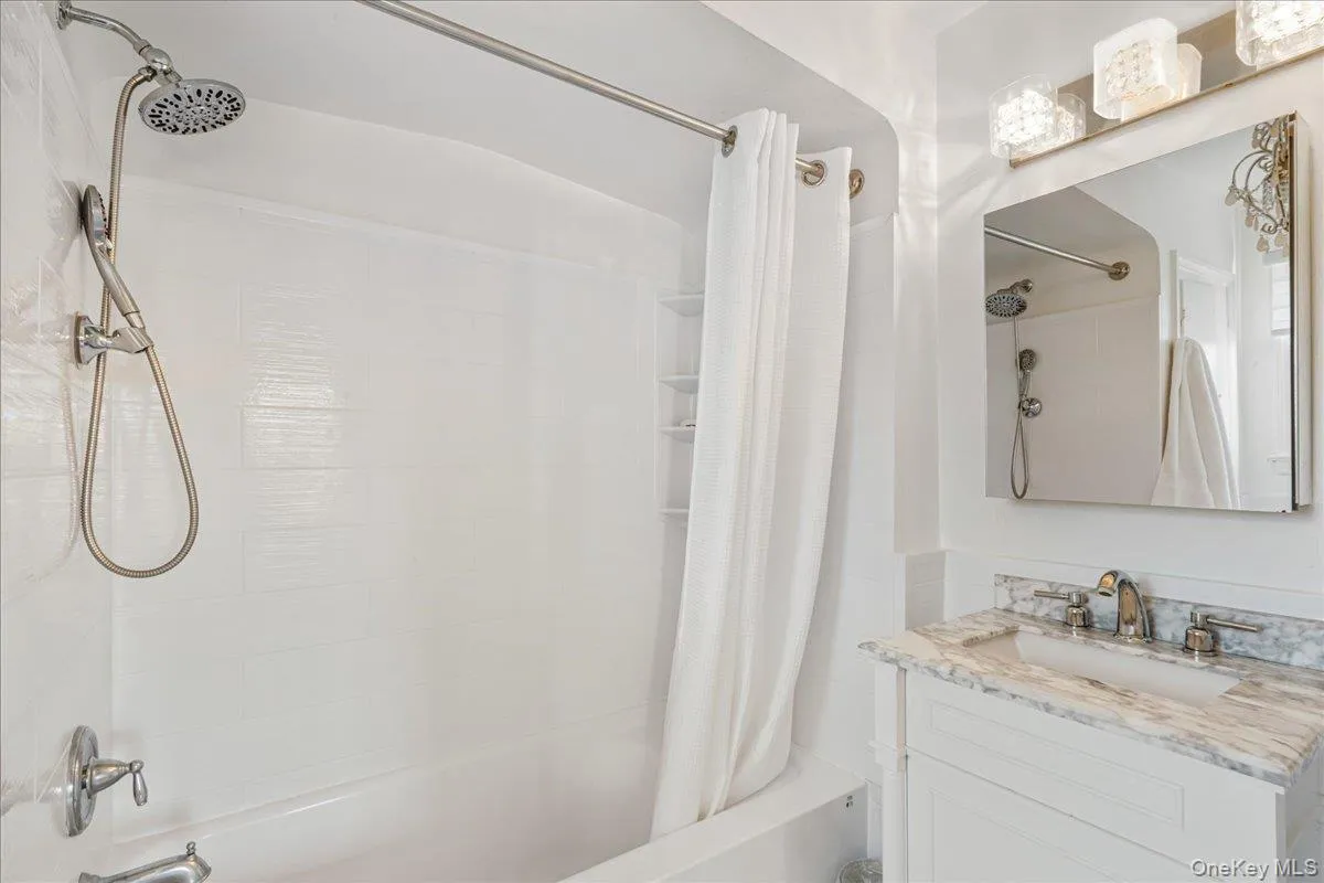 Renovated primary bathroom with marble vanity. Renovated primary bathroom with marble vanity.