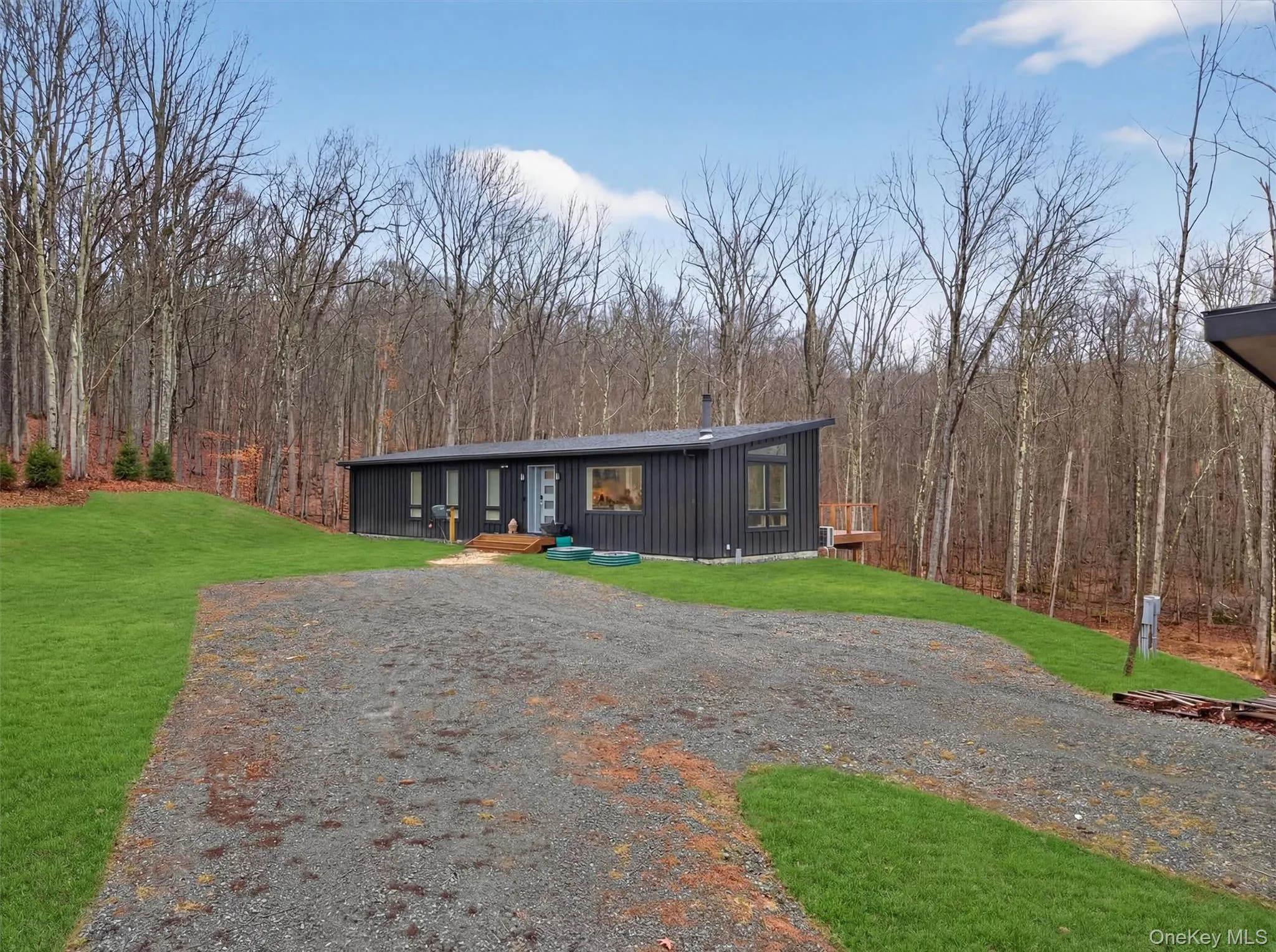 View of front of property with a front lawn, board and batten siding, and a forest view View of front of property with a front lawn, board and batten siding, and a forest view