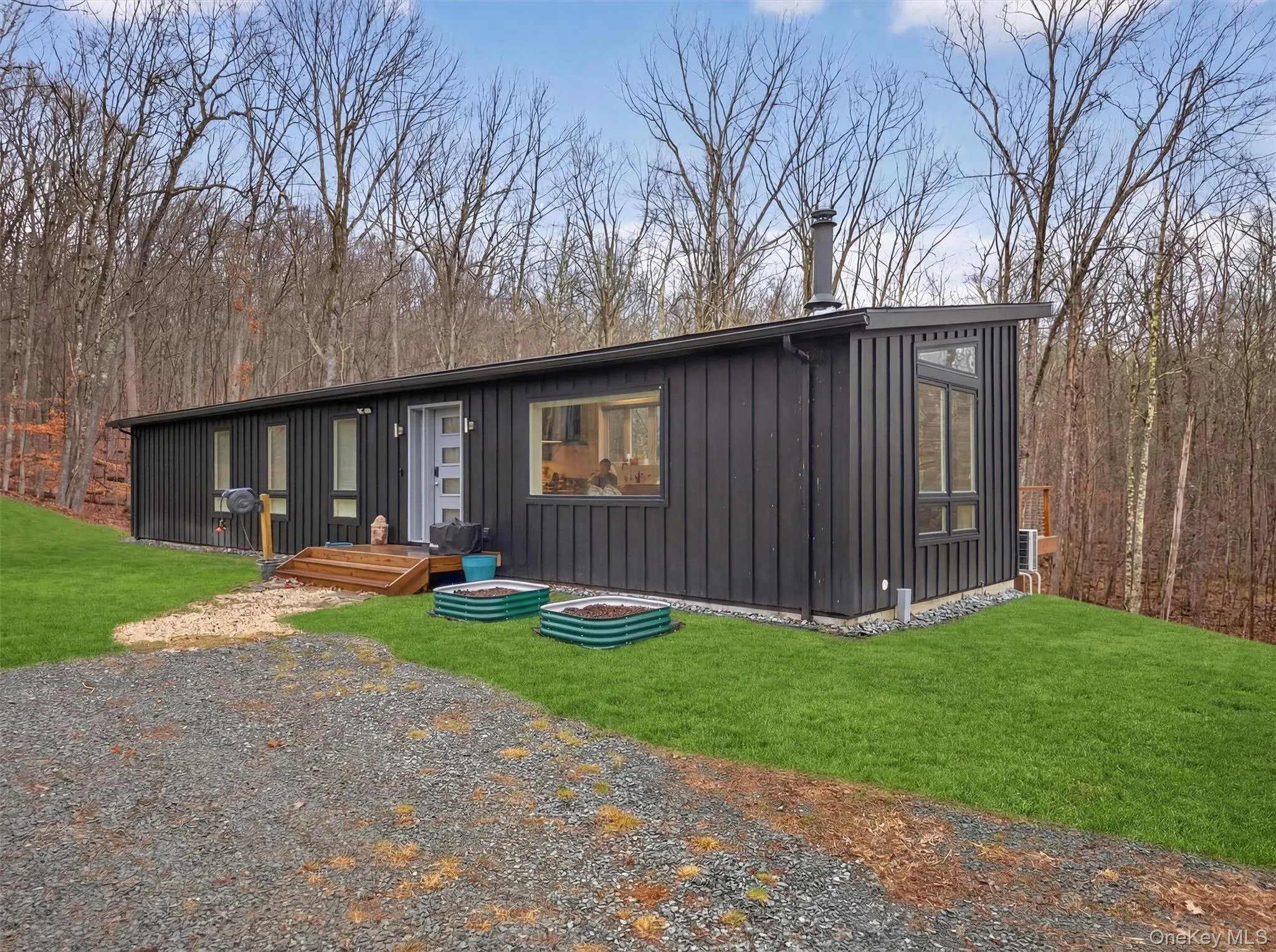 Mid-century inspired home with a front lawn and board and batten siding, raised flower bins Mid-century inspired home with a front lawn and board and batten siding, raised flower bins