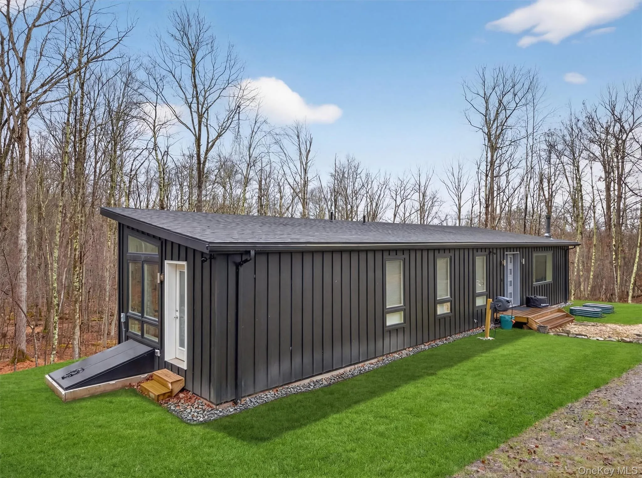 Rear view of property with board and batten siding, a lawn, a shingled roof, and entry steps Rear view of property with board and batten siding, a lawn, a shingled roof, and entry steps