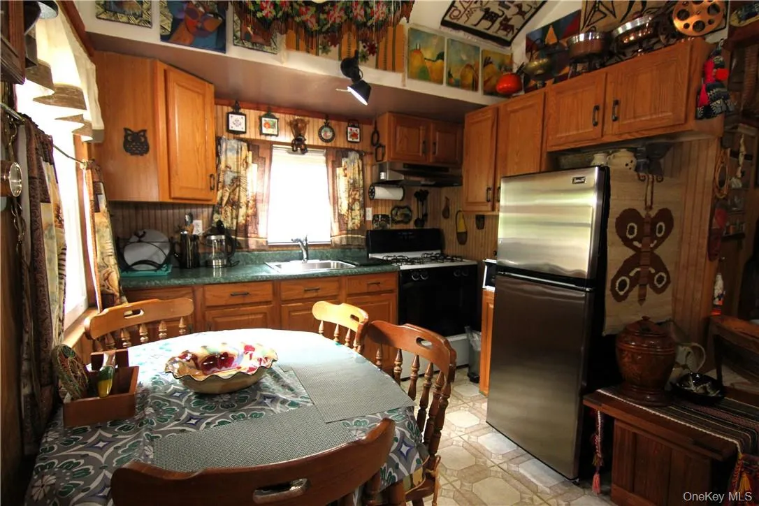 Kitchen featuring white range, sink, stainless steel fridge, and light tile floors Kitchen featuring white range, sink, stainless steel fridge, and light tile floors
