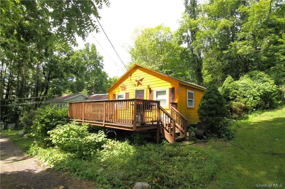 View of front of house featuring a front lawn and a wooden deck View of front of house featuring a front lawn and a wooden deck