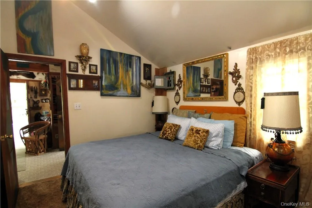 Bedroom with carpet flooring, lofted ceiling, and multiple windows Bedroom with carpet flooring, lofted ceiling, and multiple windows