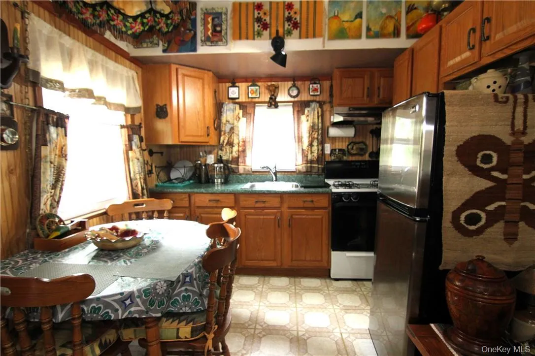 Kitchen featuring light tile flooring, sink, white range with gas stovetop, and stainless steel fridge Kitchen featuring light tile flooring, sink, white range with gas stovetop, and stainless steel fridge
