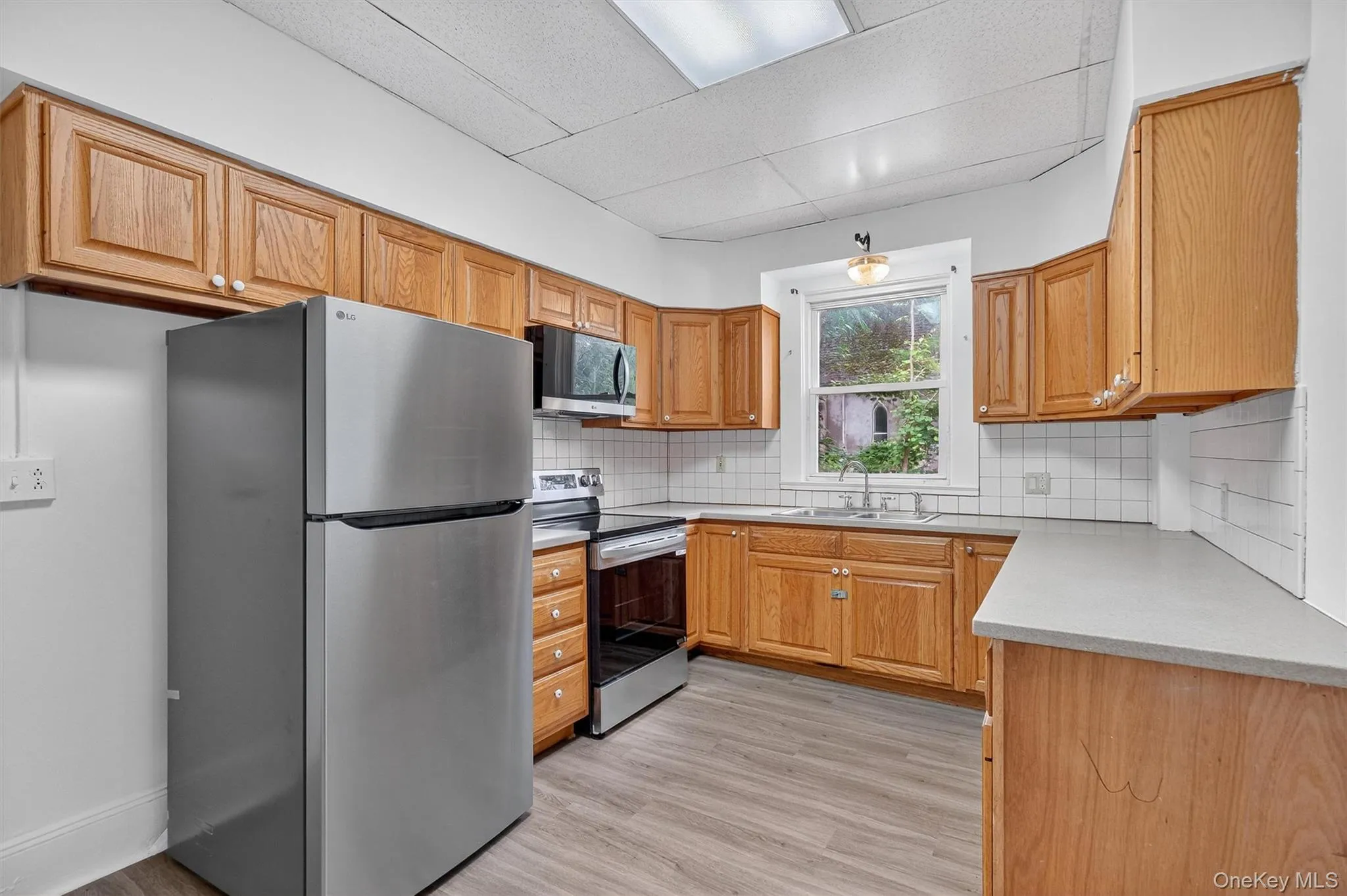 Kitchen with stainless steel appliances, backsplash, light wood-type flooring, and light countertops Kitchen with stainless steel appliances, backsplash, light wood-type flooring, and light countertops