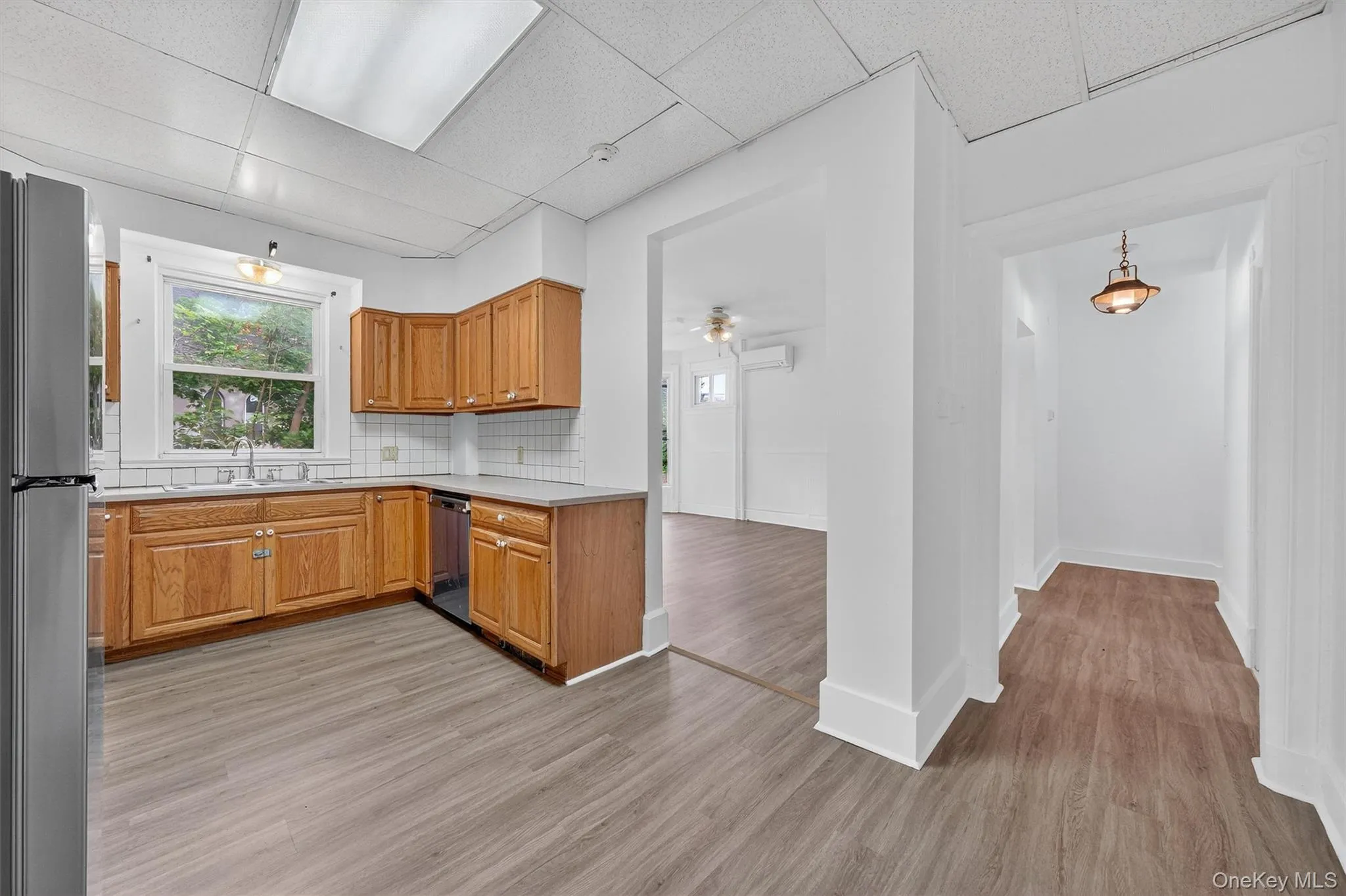 Kitchen featuring tasteful backsplash, a drop ceiling, healthy amount of natural light, light countertops, and freestanding refrigerator Kitchen featuring tasteful backsplash, a drop ceiling, healthy amount of natural light, light countertops, and freestanding refrigerator
