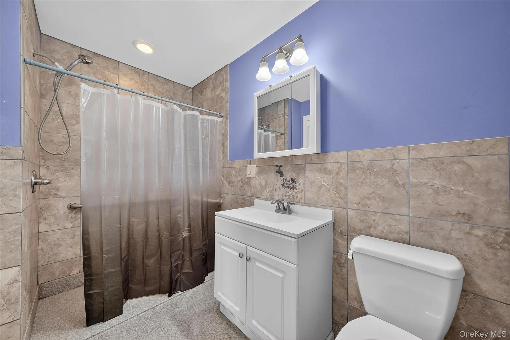 Full bath featuring vanity, tile walls, curtained shower, and recessed lighting Full bath featuring vanity, tile walls, curtained shower, and recessed lighting