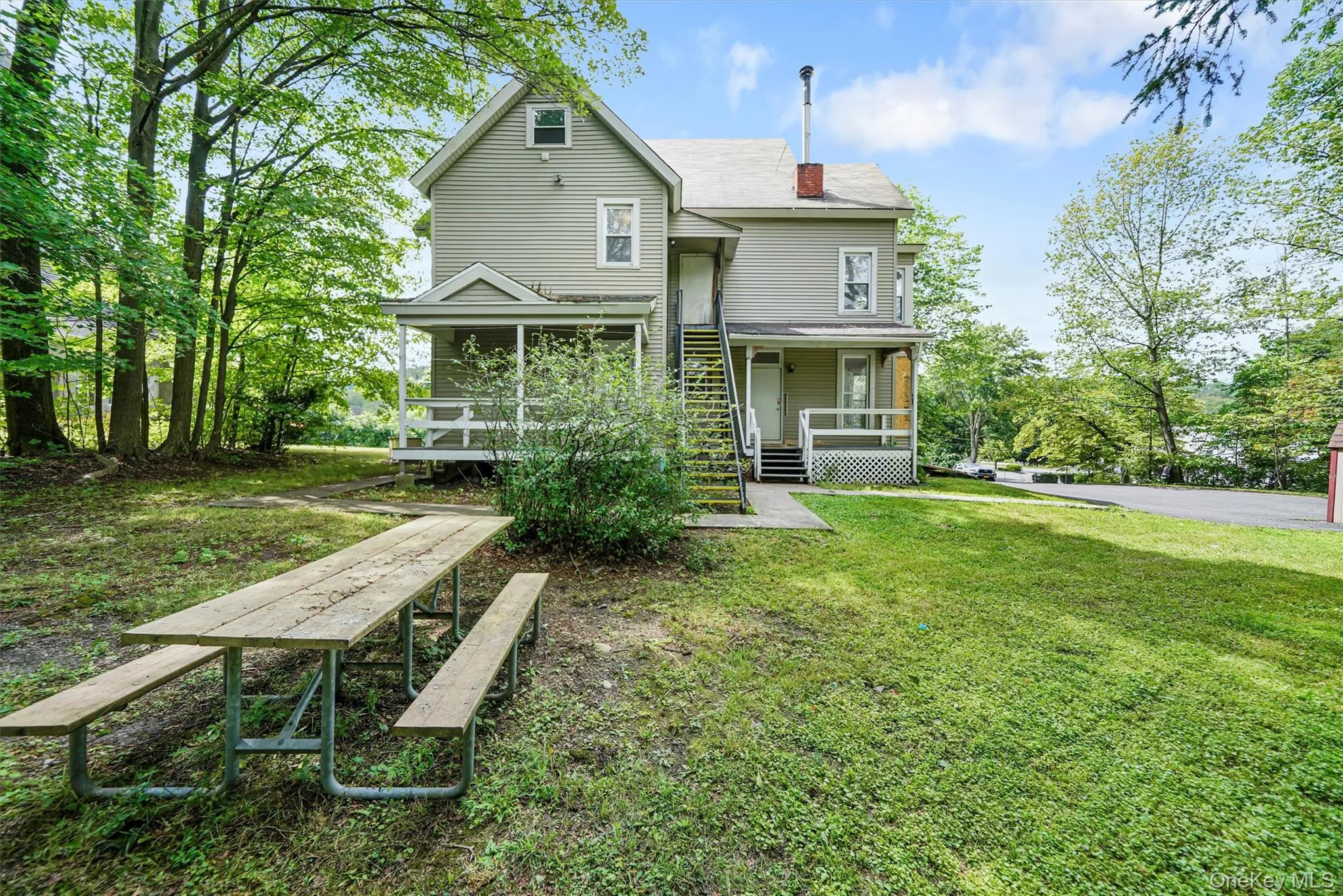 Back of house featuring a porch, a yard, and a chimney Back of house featuring a porch, a yard, and a chimney