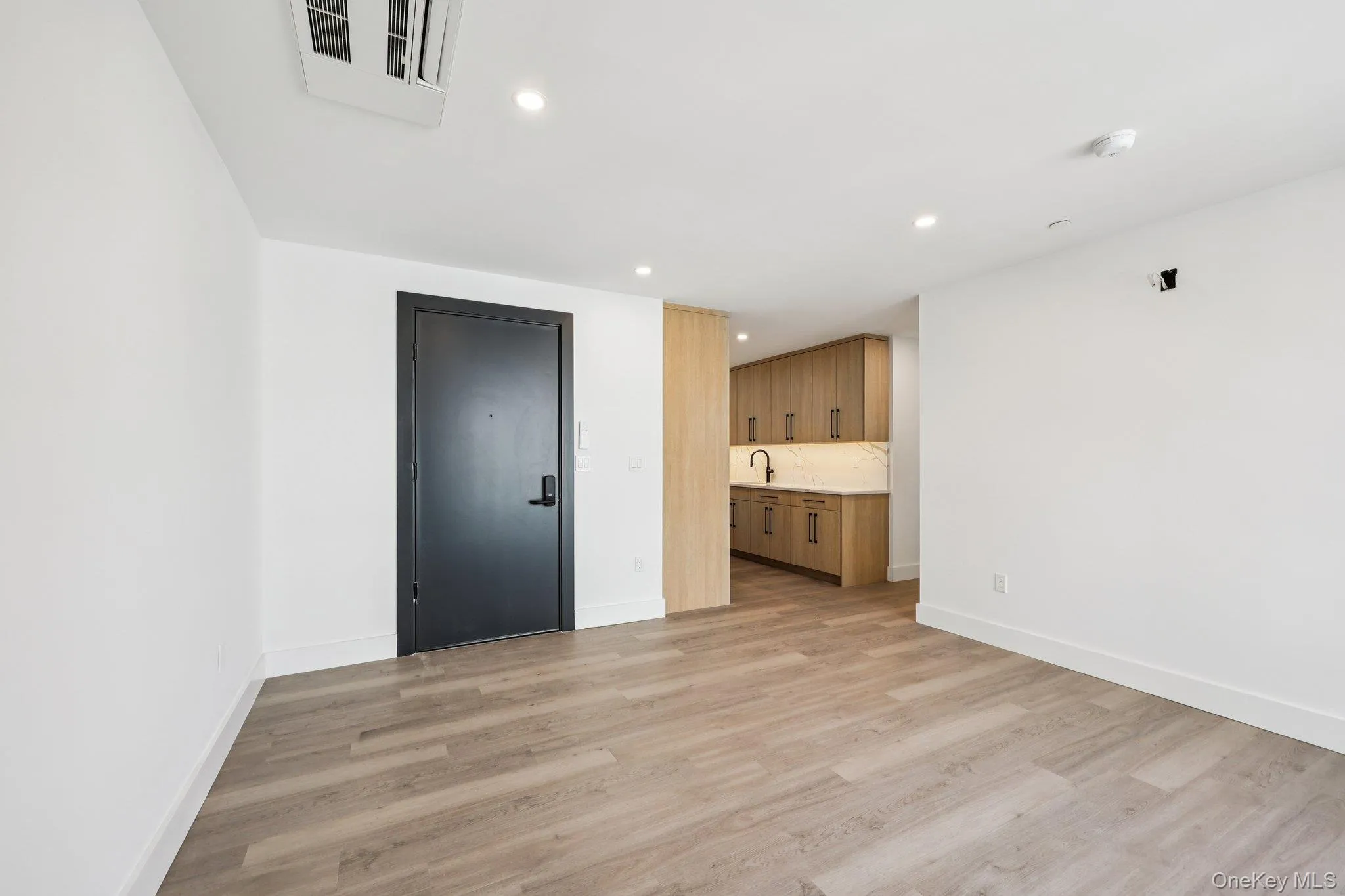 Unfurnished living room with light wood-type flooring and recessed lighting Unfurnished living room with light wood-type flooring and recessed lighting