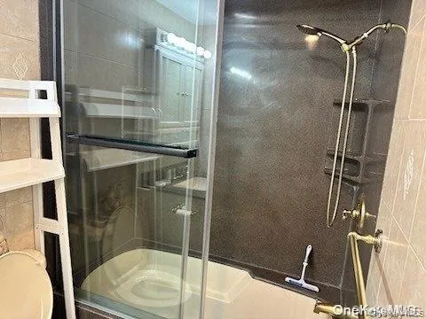 Bathroom featuring a stall shower, tile walls, and toilet Bathroom featuring a stall shower, tile walls, and toilet