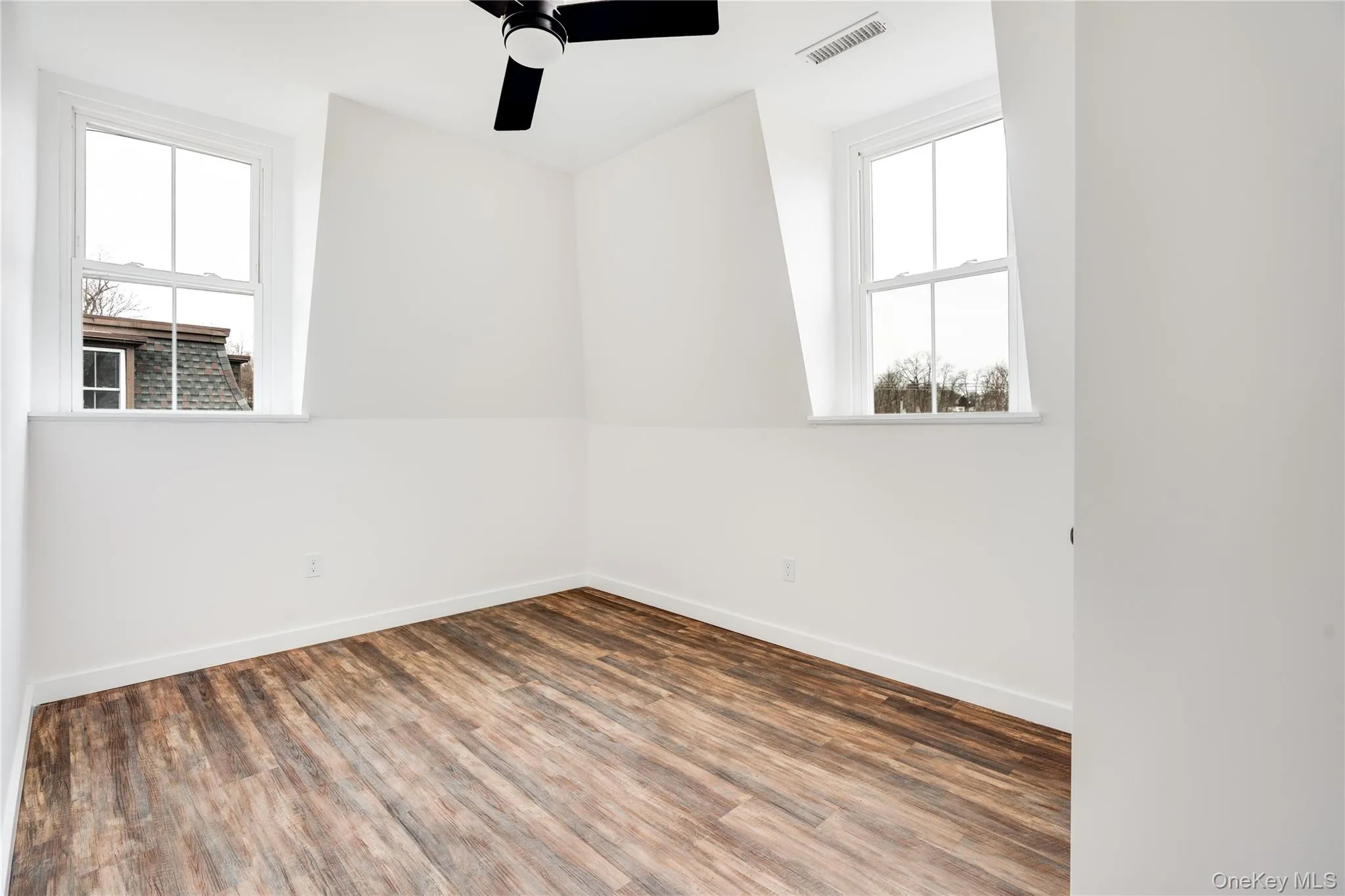 Spare room featuring ceiling fan and dark wood-type flooring Spare room featuring ceiling fan and dark wood-type flooring