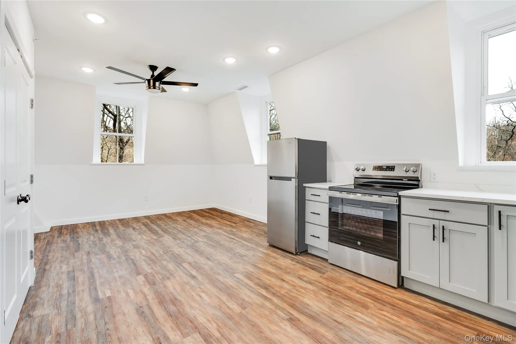 Kitchen featuring ceiling fan, appliances with stainless steel finishes, gray cabinetry, and light wood-type flooring Kitchen featuring ceiling fan, appliances with stainless steel finishes, gray cabinetry, and light wood-type flooring