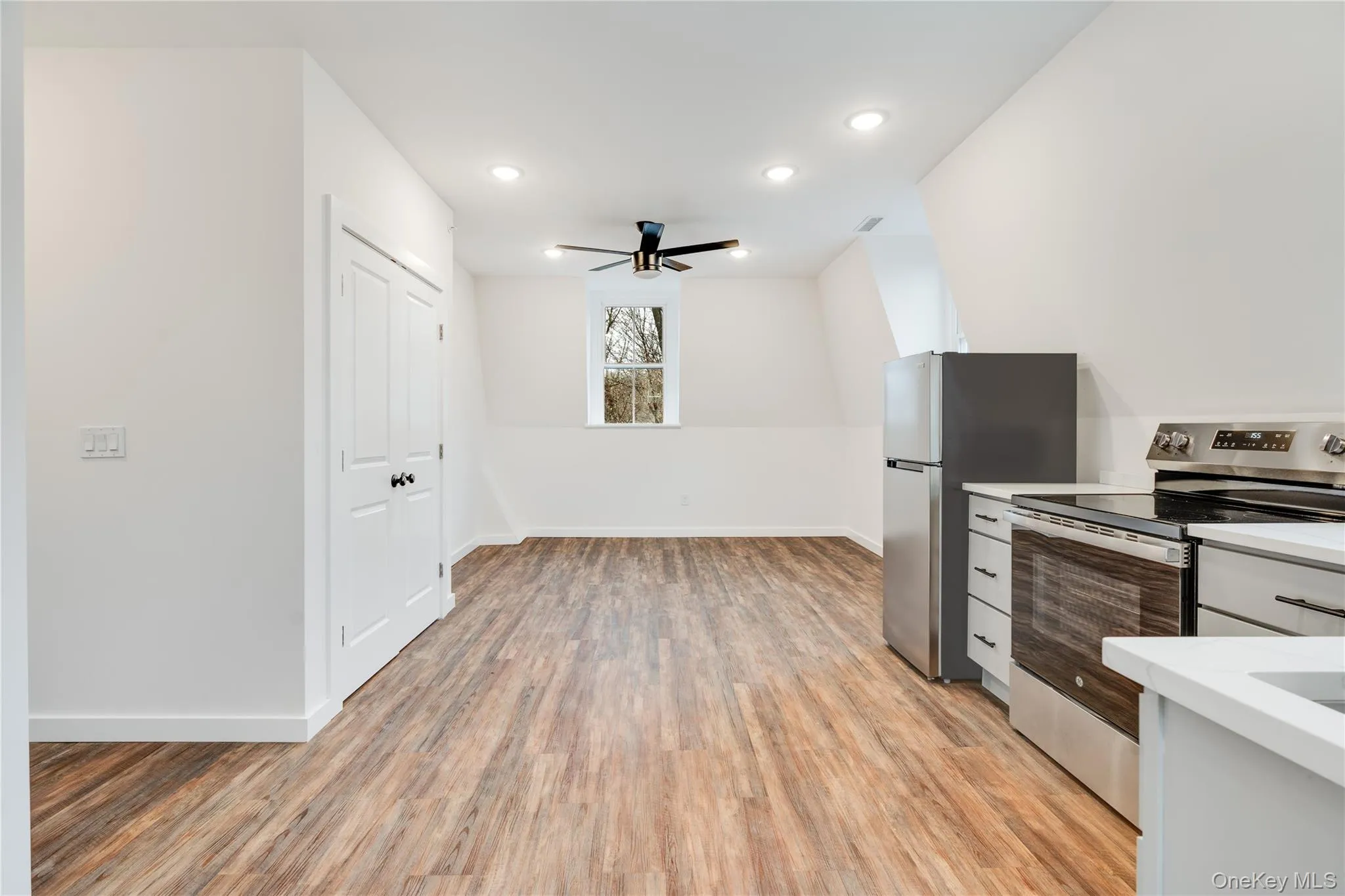 Kitchen featuring light hardwood / wood-style flooring, ceiling fan, and appliances with stainless steel finishes Kitchen featuring light hardwood / wood-style flooring, ceiling fan, and appliances with stainless steel finishes