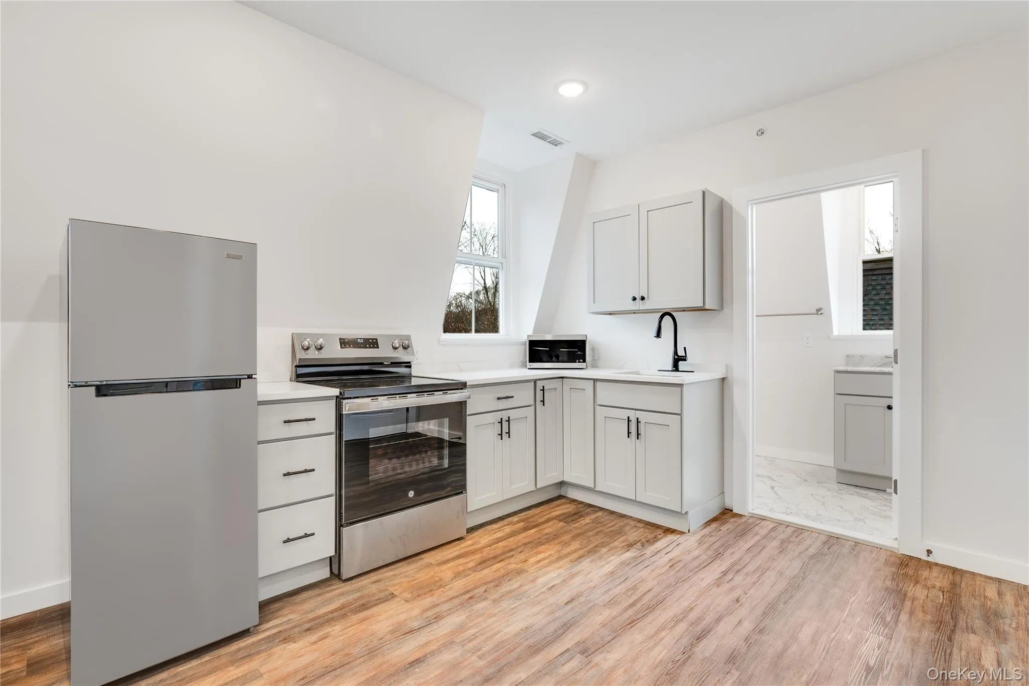 Kitchen featuring sink, light hardwood / wood-style flooring, and appliances with stainless steel finishes Kitchen featuring sink, light hardwood / wood-style flooring, and appliances with stainless steel finishes