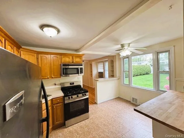 Eat-in-Kitchen area featuring wood-finish cabinetry, stainless steel appliances, a gas range, and a ceiling fan. Eat-in-Kitchen area featuring wood-finish cabinetry, stainless steel appliances, a gas range, and a ceiling fan.