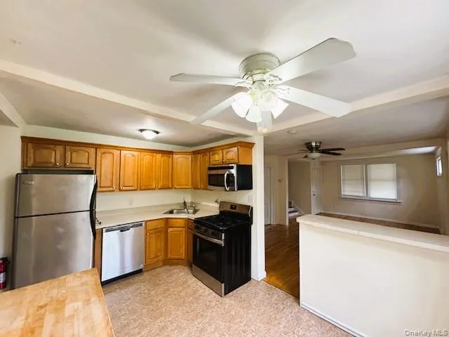 Eat-in-Kitchen Featuring wood cabinetry, Stainless Steel Appliances, corner sink, Middle Island for Four and a ceiling fan Eat-in-Kitchen Featuring wood cabinetry, Stainless Steel Appliances, corner sink, Middle Island for Four and a ceiling fan
