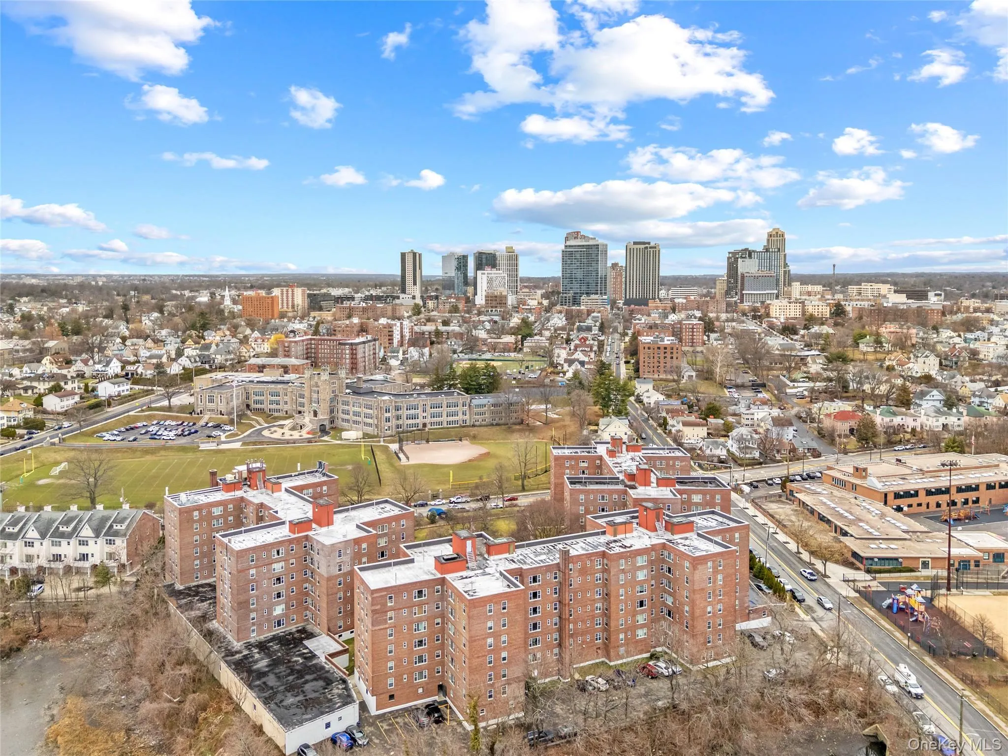 Aerial view of the building complex with the vibrant skyline of downtown New Rochelle in the background, highlighting the property’s convenient location near shopping, dining, transportation, and the waterfront. Aerial view of the building complex with the vibrant skyline of downtown New Rochelle in the background, highlighting the property’s convenient location near shopping, dining, transportation, and the waterfront.
