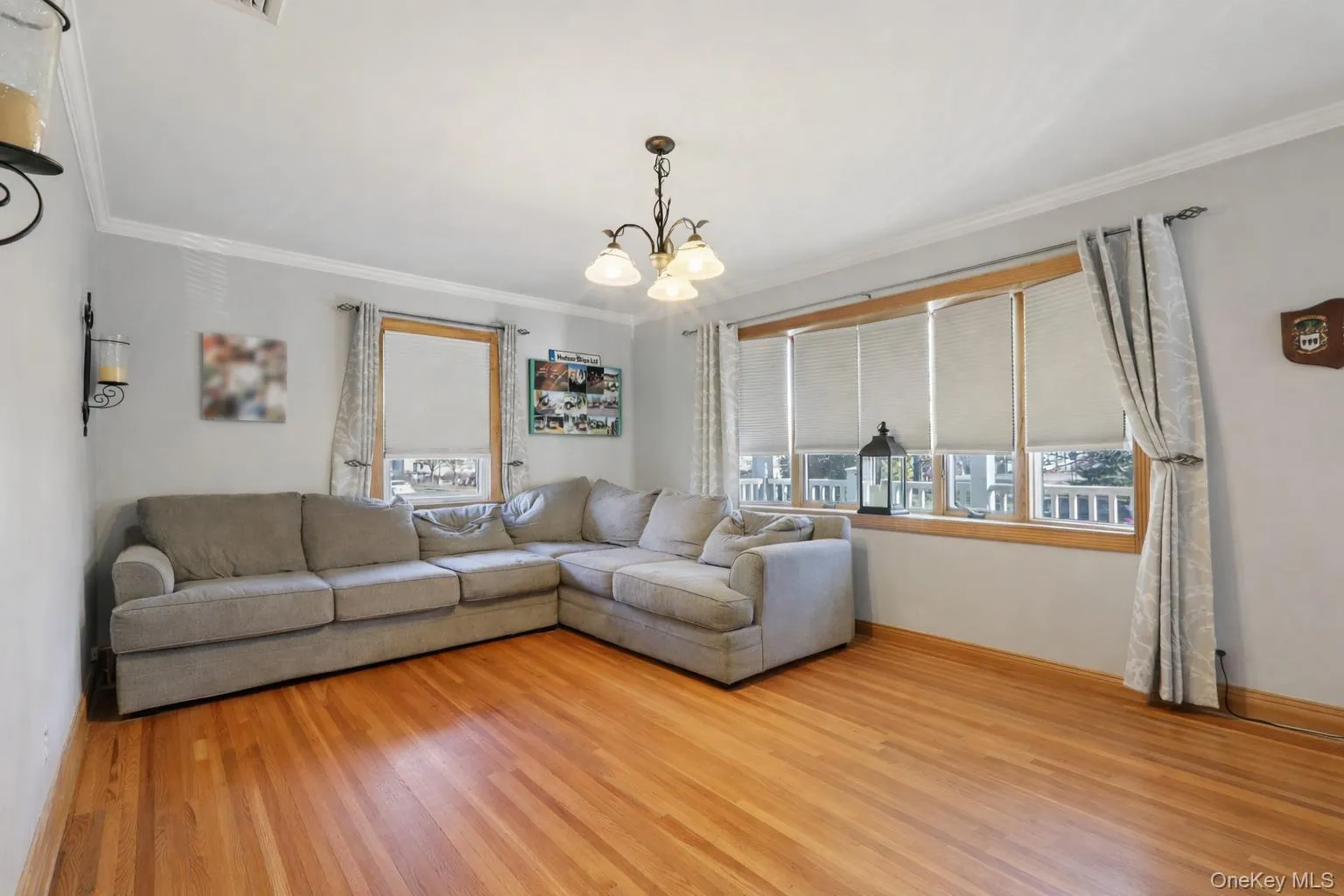 Living area with hanging lights, ornamental molding, and light wood-style flooring Living area with hanging lights, ornamental molding, and light wood-style flooring