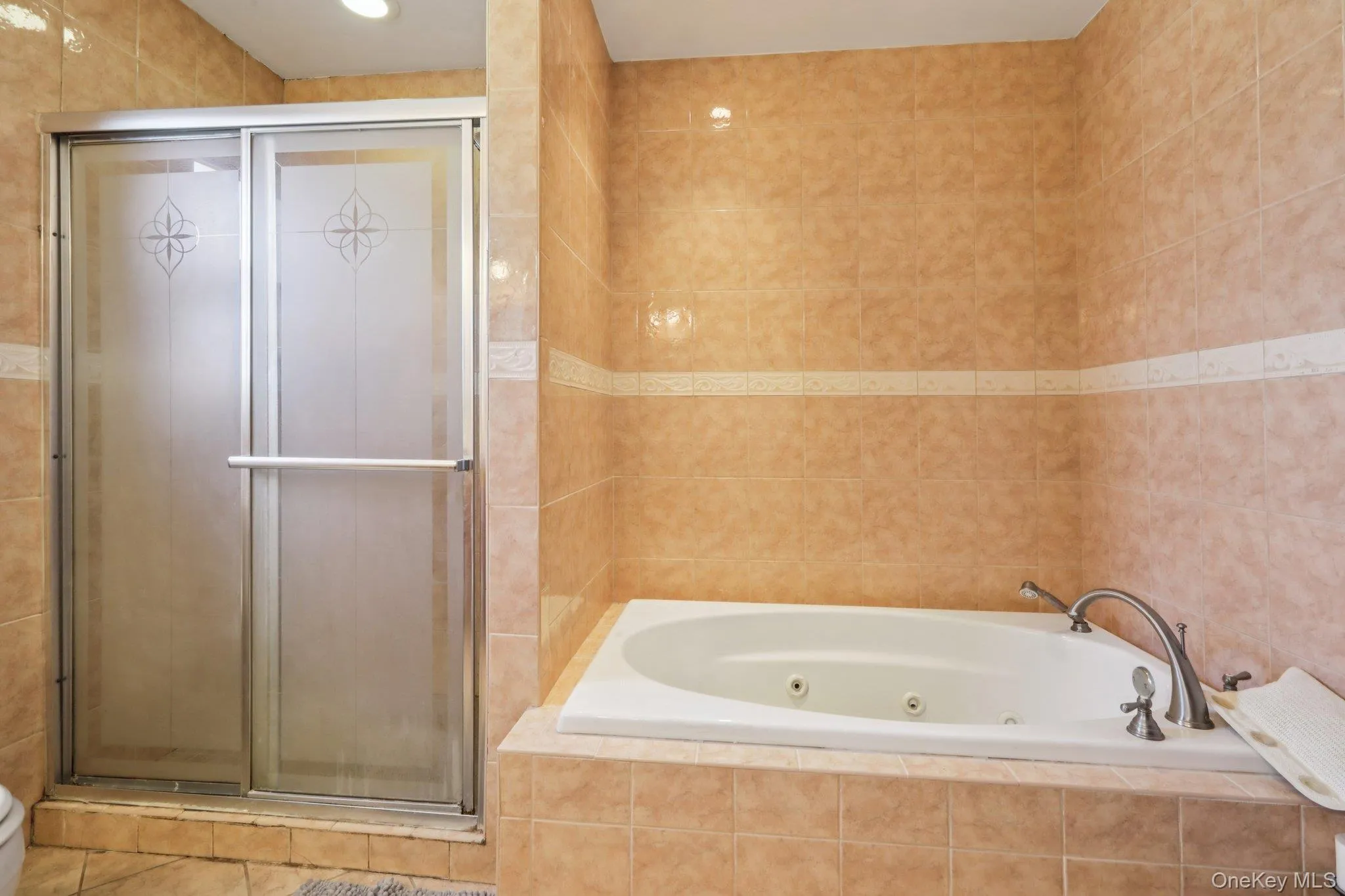Full bathroom featuring a stall shower, a jetted tub, and tile walls Full bathroom featuring a stall shower, a jetted tub, and tile walls