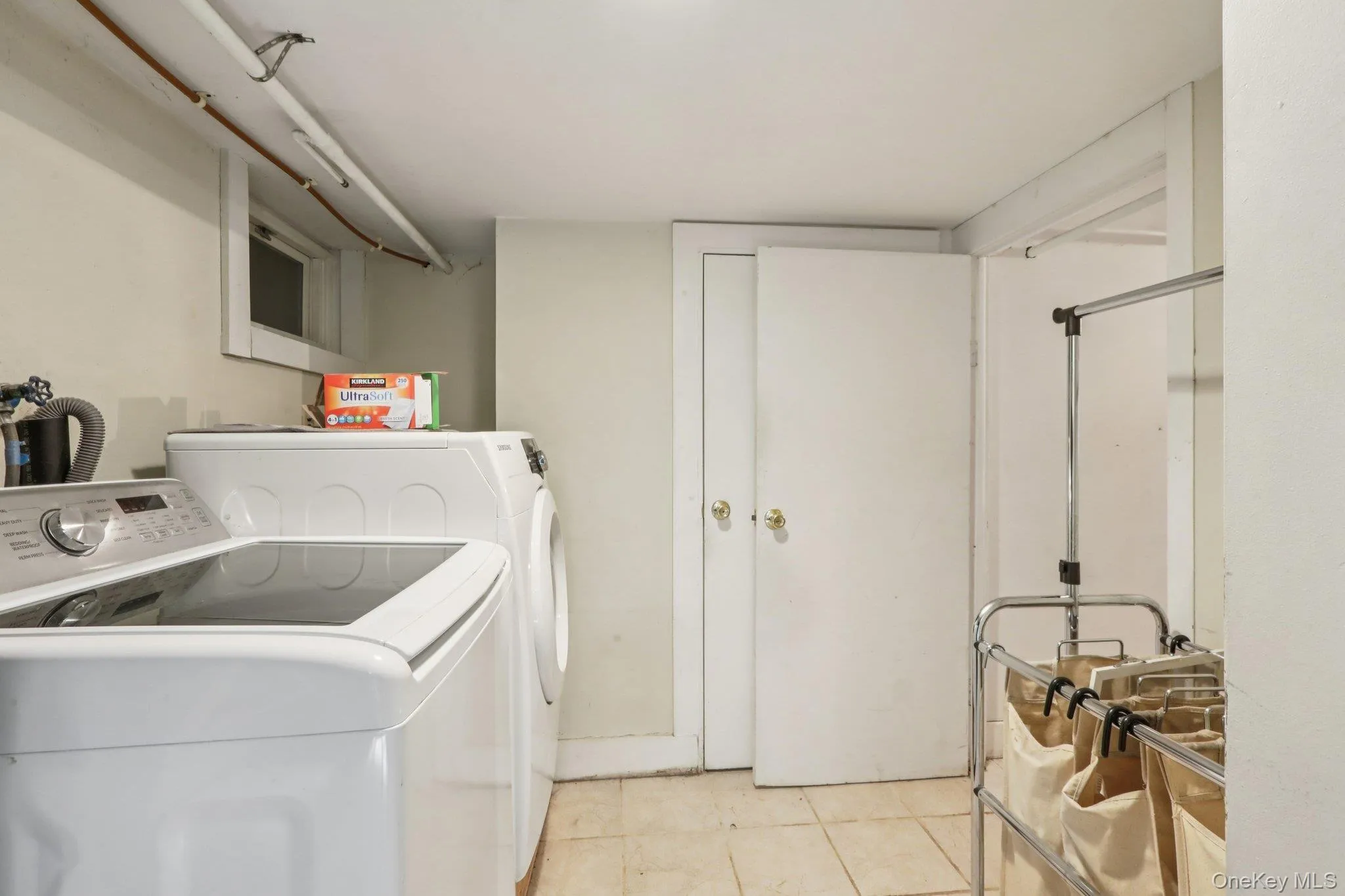 Laundry room with washing machine and clothes dryer and light tile patterned floors Laundry room with washing machine and clothes dryer and light tile patterned floors