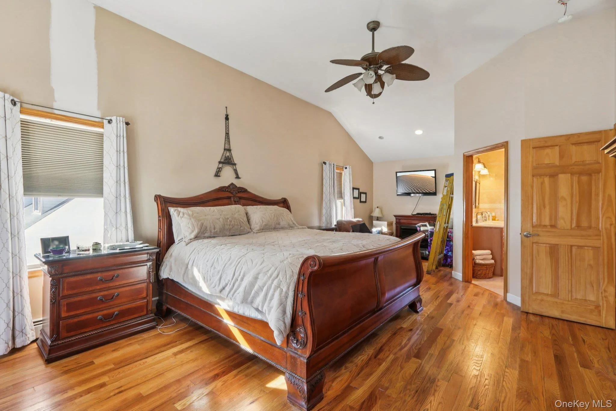 Bedroom featuring light wood-style floors, vaulted ceiling, ceiling fan, and connected bathroom Bedroom featuring light wood-style floors, vaulted ceiling, ceiling fan, and connected bathroom
