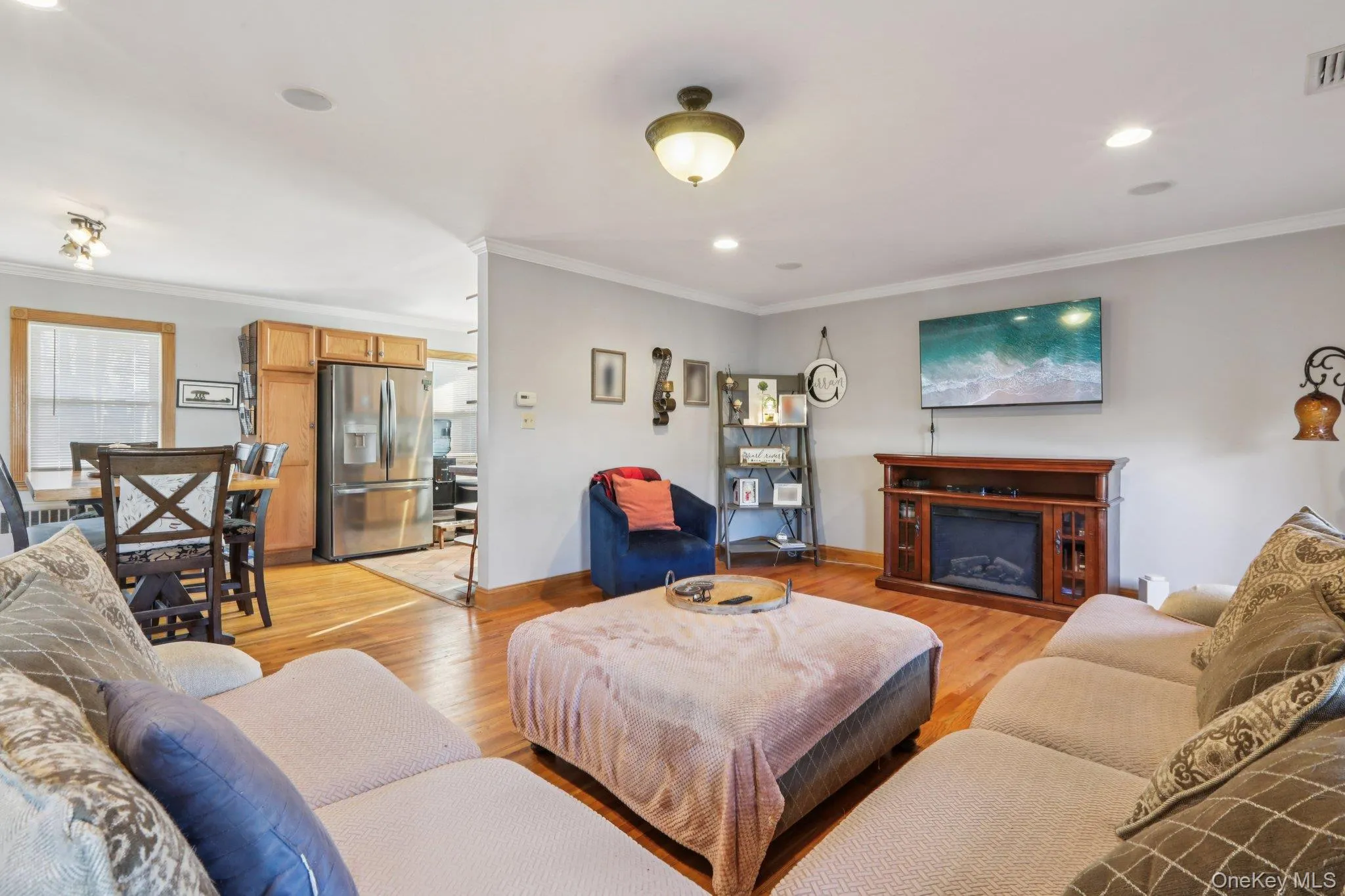 Living area featuring ornamental molding, light wood-type flooring, a fireplace, and recessed lighting Living area featuring ornamental molding, light wood-type flooring, a fireplace, and recessed lighting