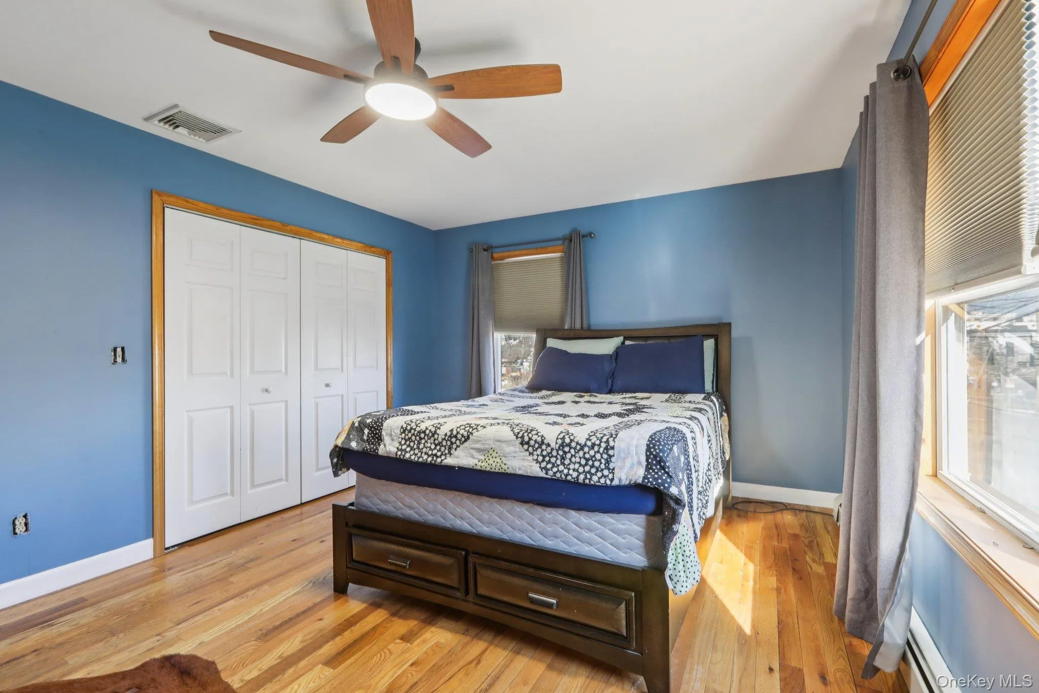 Bedroom with light wood-type flooring, a baseboard radiator, ceiling fan, and a closet Bedroom with light wood-type flooring, a baseboard radiator, ceiling fan, and a closet