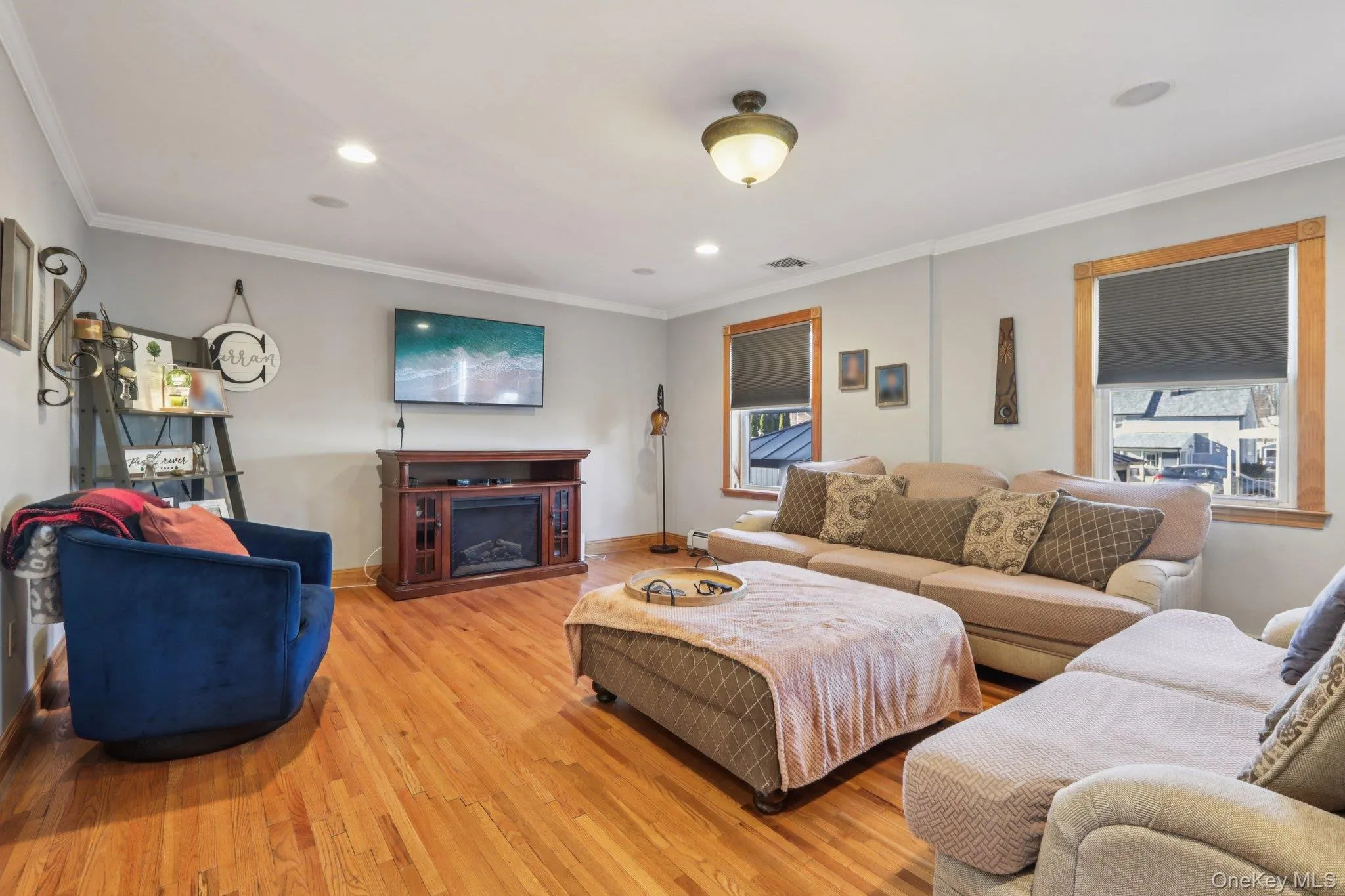 Living room featuring wood finished floors, crown molding, recessed lighting, and a fireplace Living room featuring wood finished floors, crown molding, recessed lighting, and a fireplace