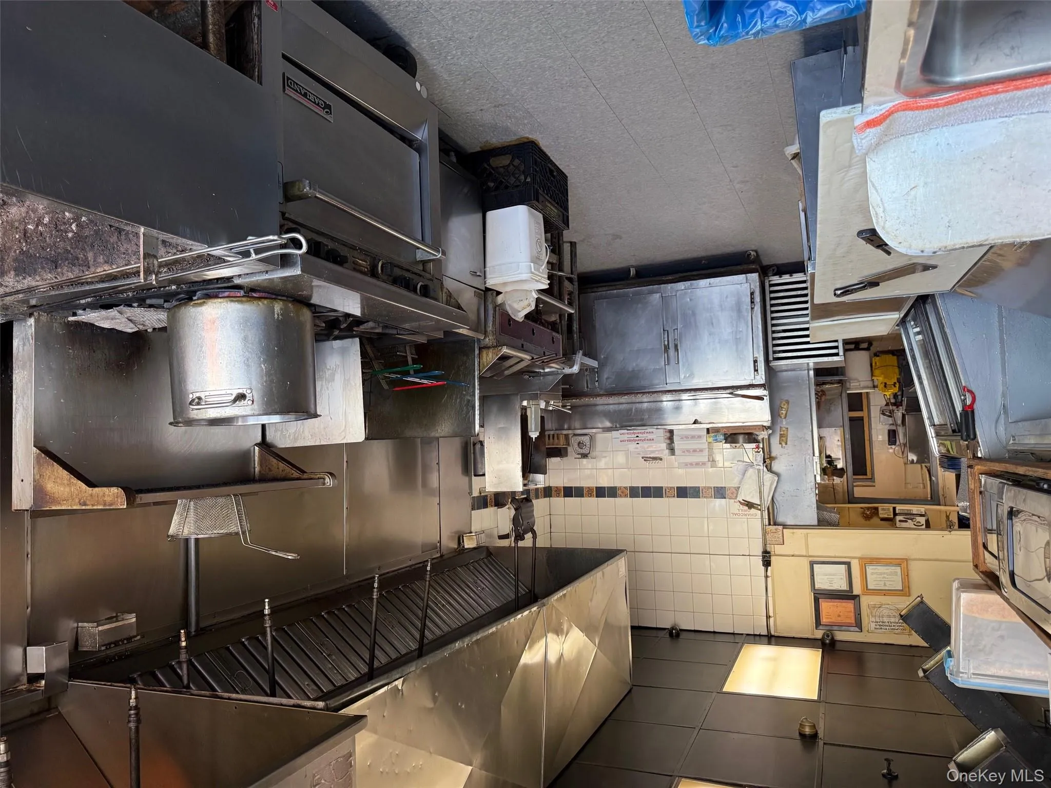 Kitchen featuring decorative backsplash, tile patterned floors, and stainless steel countertops Kitchen featuring decorative backsplash, tile patterned floors, and stainless steel countertops