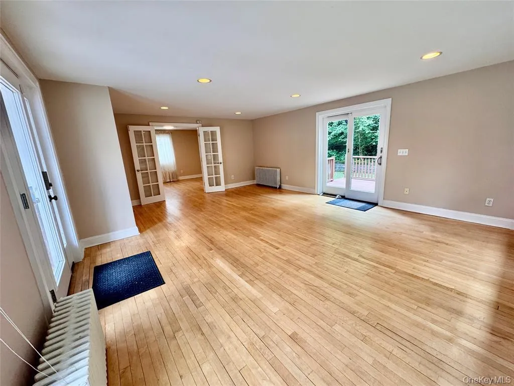 Sunny living room featuring french doors, light wood finished floors, recessed lighting,and access to outdoor deck Sunny living room featuring french doors, light wood finished floors, recessed lighting,and access to outdoor deck