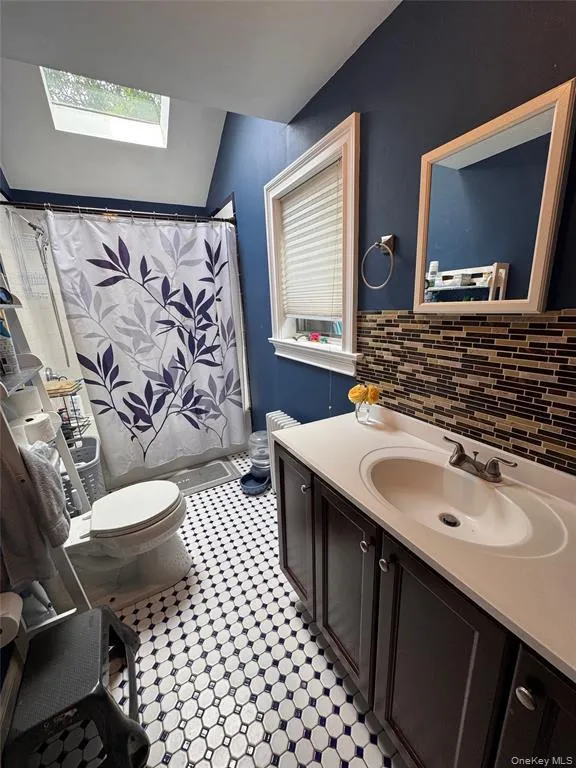 Full bathroom on lower level with a skylight, toilet, vanity, lofted ceiling, and tub/shower Full bathroom on lower level with a skylight, toilet, vanity, lofted ceiling, and tub/shower
