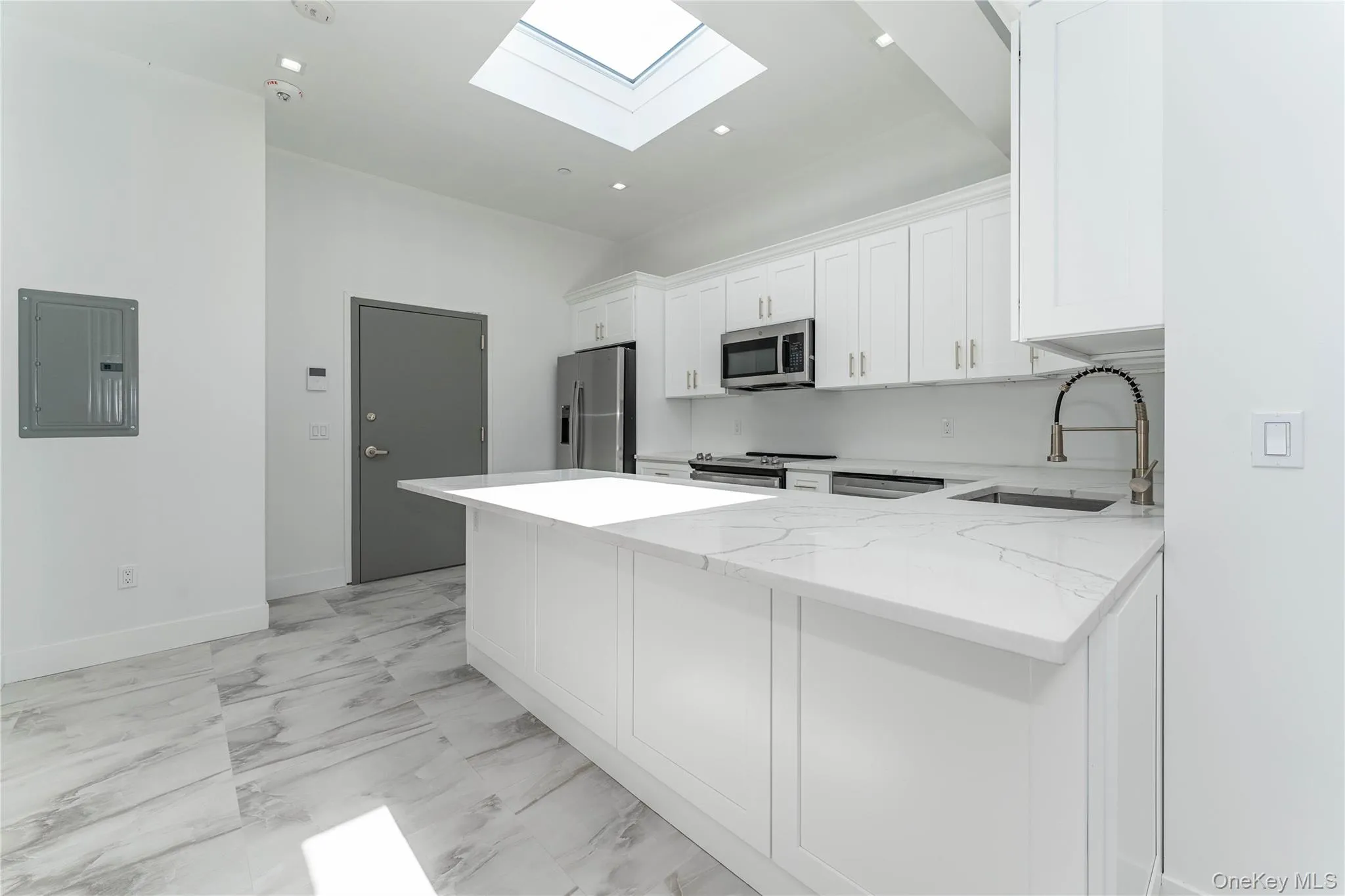 Kitchen with stainless steel appliances, electric panel, a sink, a skylight, and white cabinetry Kitchen with stainless steel appliances, electric panel, a sink, a skylight, and white cabinetry