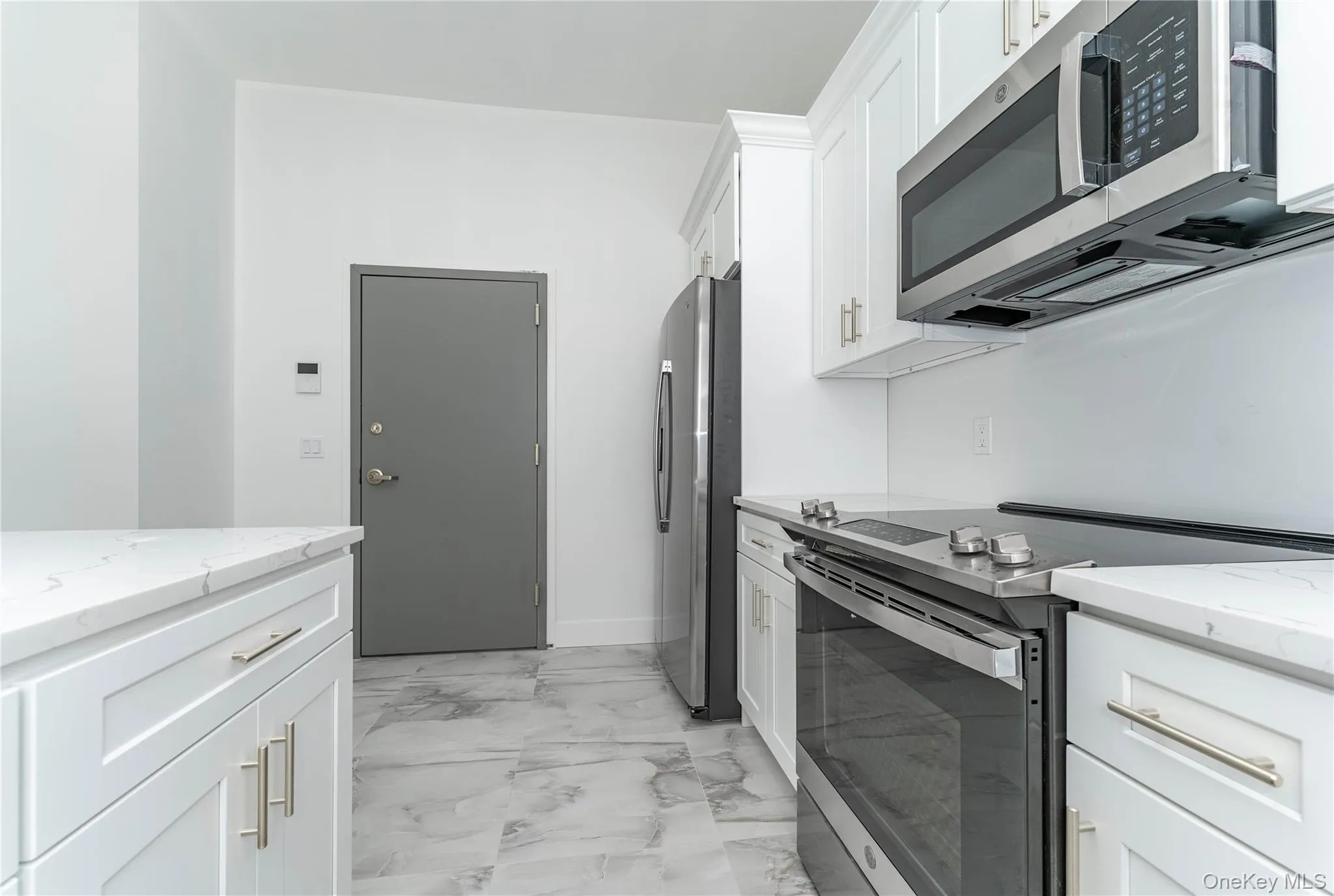 Kitchen with appliances with stainless steel finishes, light marble finish flooring, white cabinetry, light stone countertops, and baseboards Kitchen with appliances with stainless steel finishes, light marble finish flooring, white cabinetry, light stone countertops, and baseboards