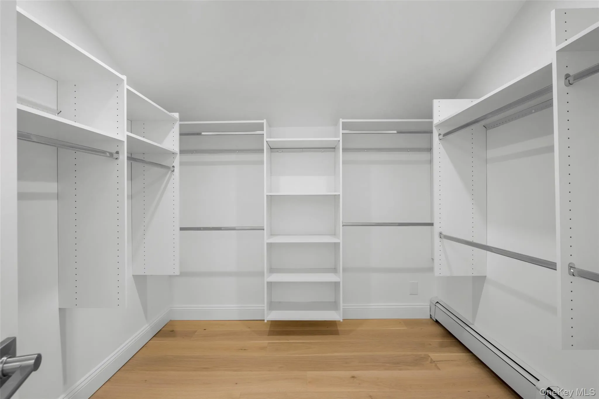 Expansive primary suite walk-in closet, it provides versatile hanging space and built-in shelving designed to accommodate an extensive wardrobe. Expansive primary suite walk-in closet, it provides versatile hanging space and built-in shelving designed to accommodate an extensive wardrobe.