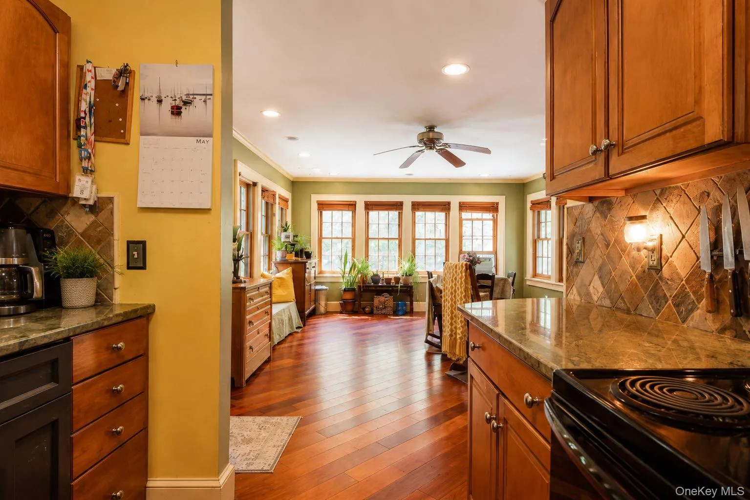 Kitchen featuring wood cabinetry, stone-finish countertops, and a tiled backsplash Kitchen featuring wood cabinetry, stone-finish countertops, and a tiled backsplash