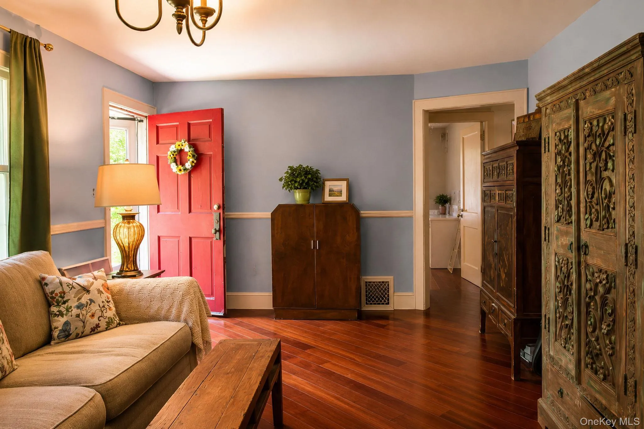 Vibrant red entry door opening into a room featuring Brazilian cherry wood flooring Vibrant red entry door opening into a room featuring Brazilian cherry wood flooring