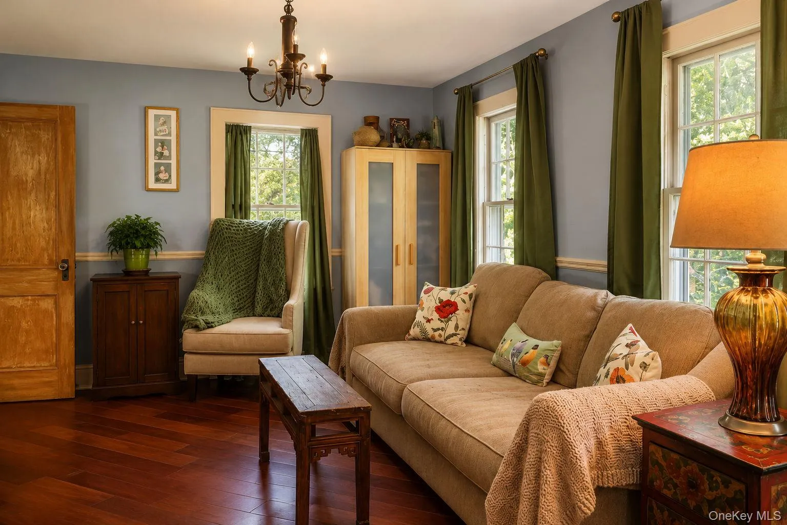 Living room featuring Brazilian cherry wood flooring, a chandelier, and multiple windows Living room featuring Brazilian cherry wood flooring, a chandelier, and multiple windows