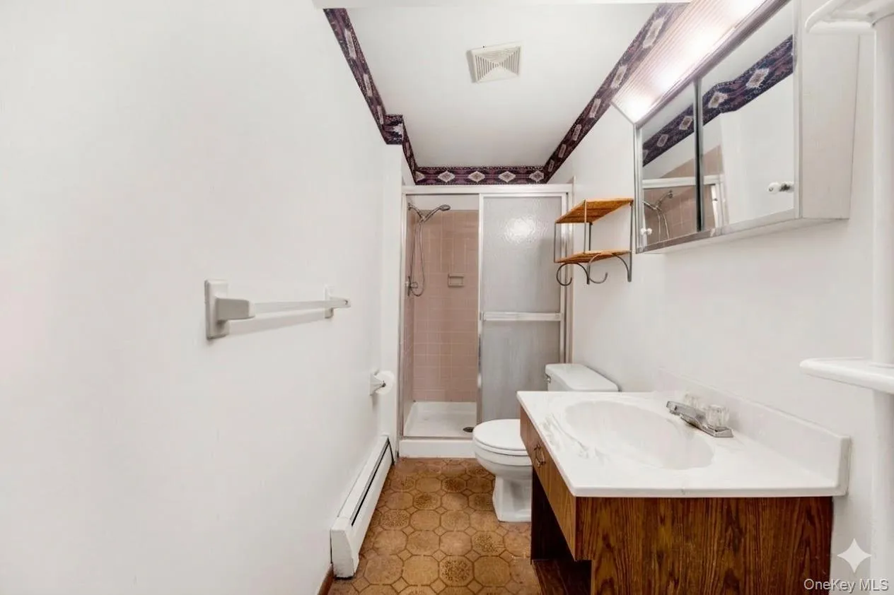 Full bathroom with a baseboard radiator, a shower stall, and vanity Full bathroom with a baseboard radiator, a shower stall, and vanity