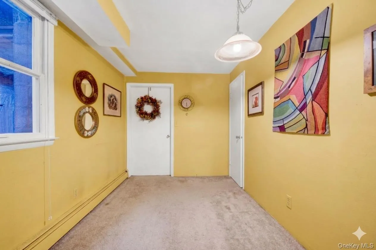 Hallway featuring baseboard heating and light carpet Hallway featuring baseboard heating and light carpet