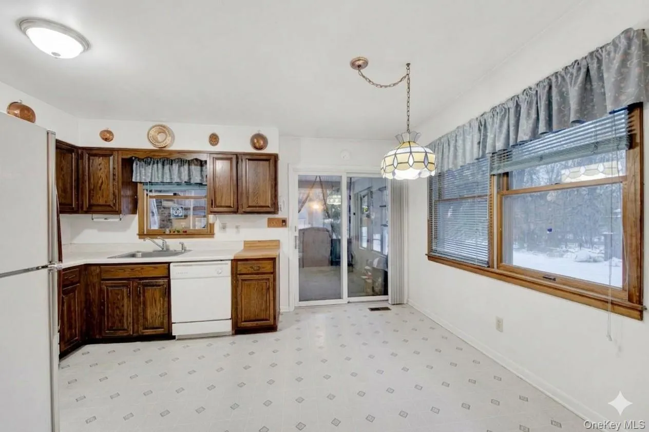 Kitchen with light flooring, light countertops, white appliances, and hanging light fixtures Kitchen with light flooring, light countertops, white appliances, and hanging light fixtures